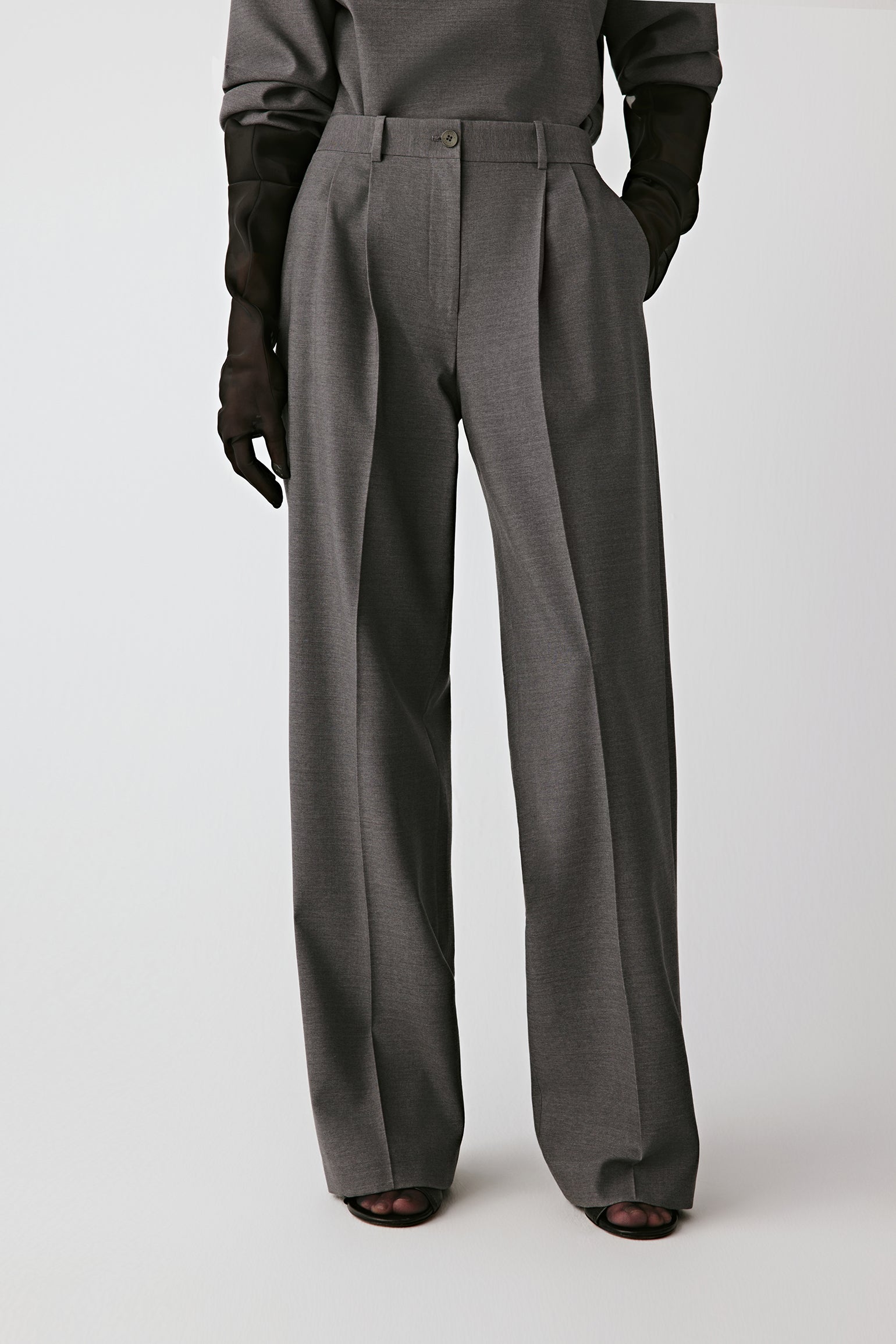 Three-quarter front view showing the sharp pleats and belted waistband.