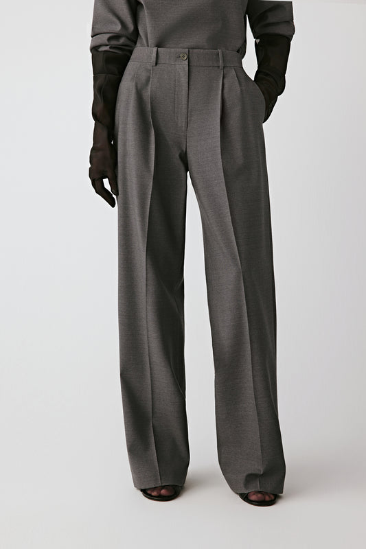 Three-quarter front view showing the sharp pleats and belted waistband.