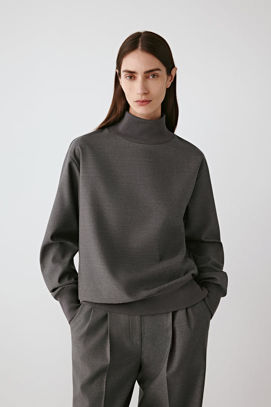 Front view of the grey wool sateen blouse, high collar and long sleeves, paired with matching trousers.