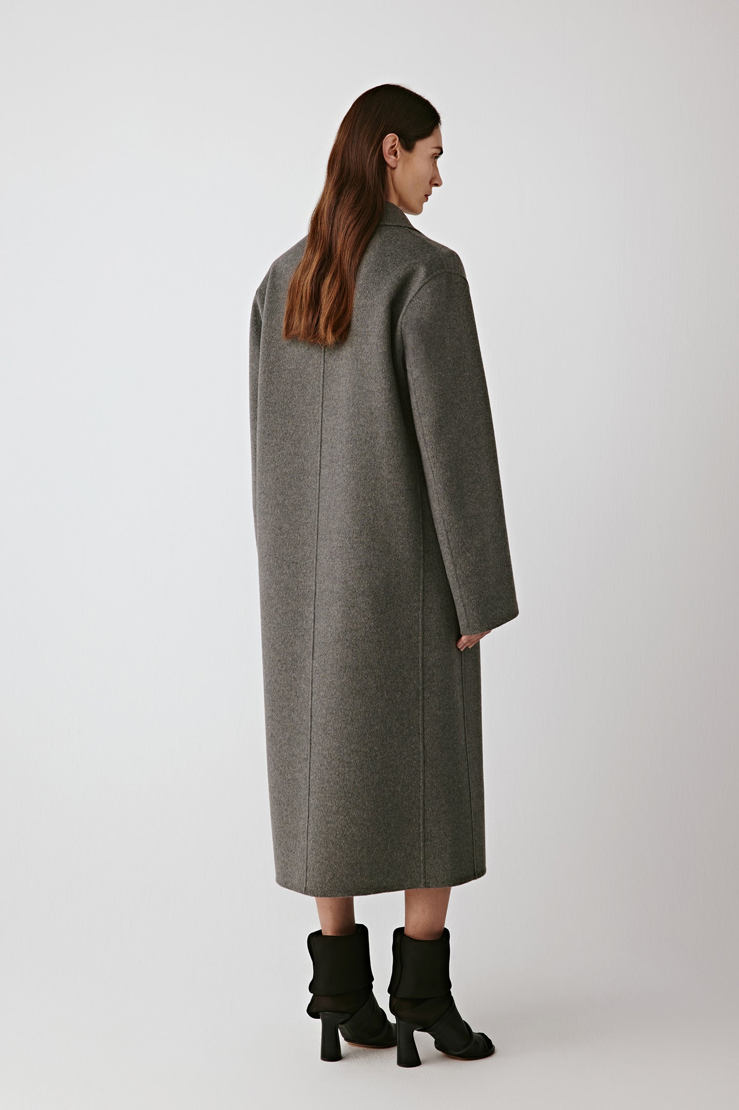 Back view of the coat, displaying its straight cut and elegant movement.