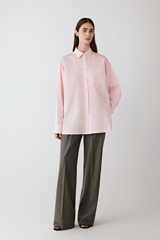 Full-length front view of the model wearing the lilac-pink cotton poplin shirt paired with wide grey trousers, showing the shirt’s crisp and lightweight texture.