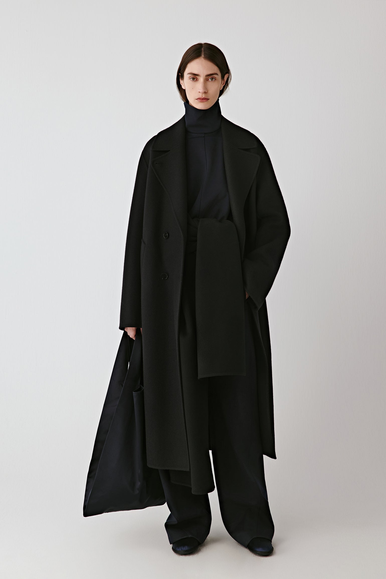 Front view of the deep blue-black double-faced wool coat, featuring wide notched lapels and a double-breasted closure.