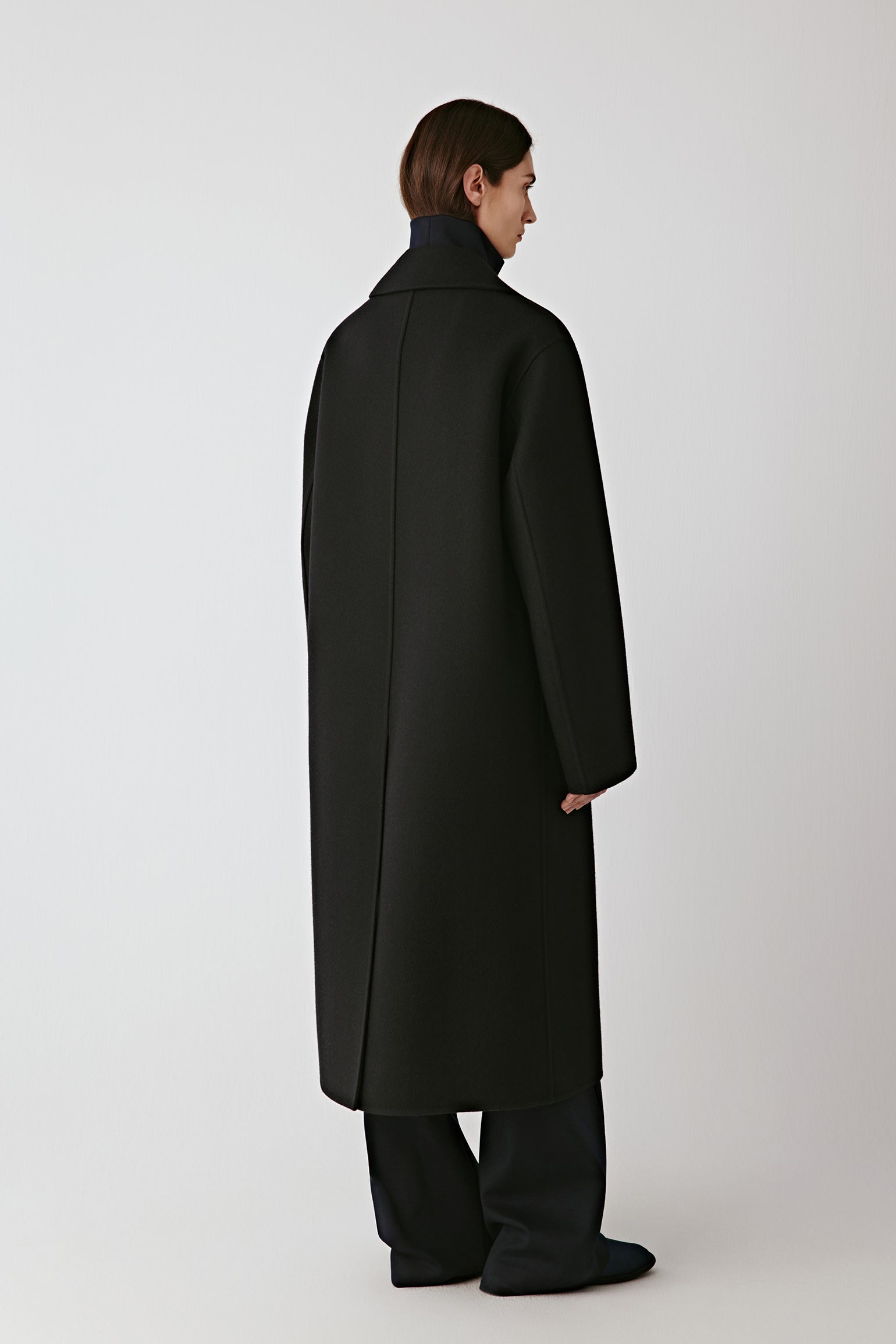Side view of the long coat, showing its elegant length and tailored silhouette.