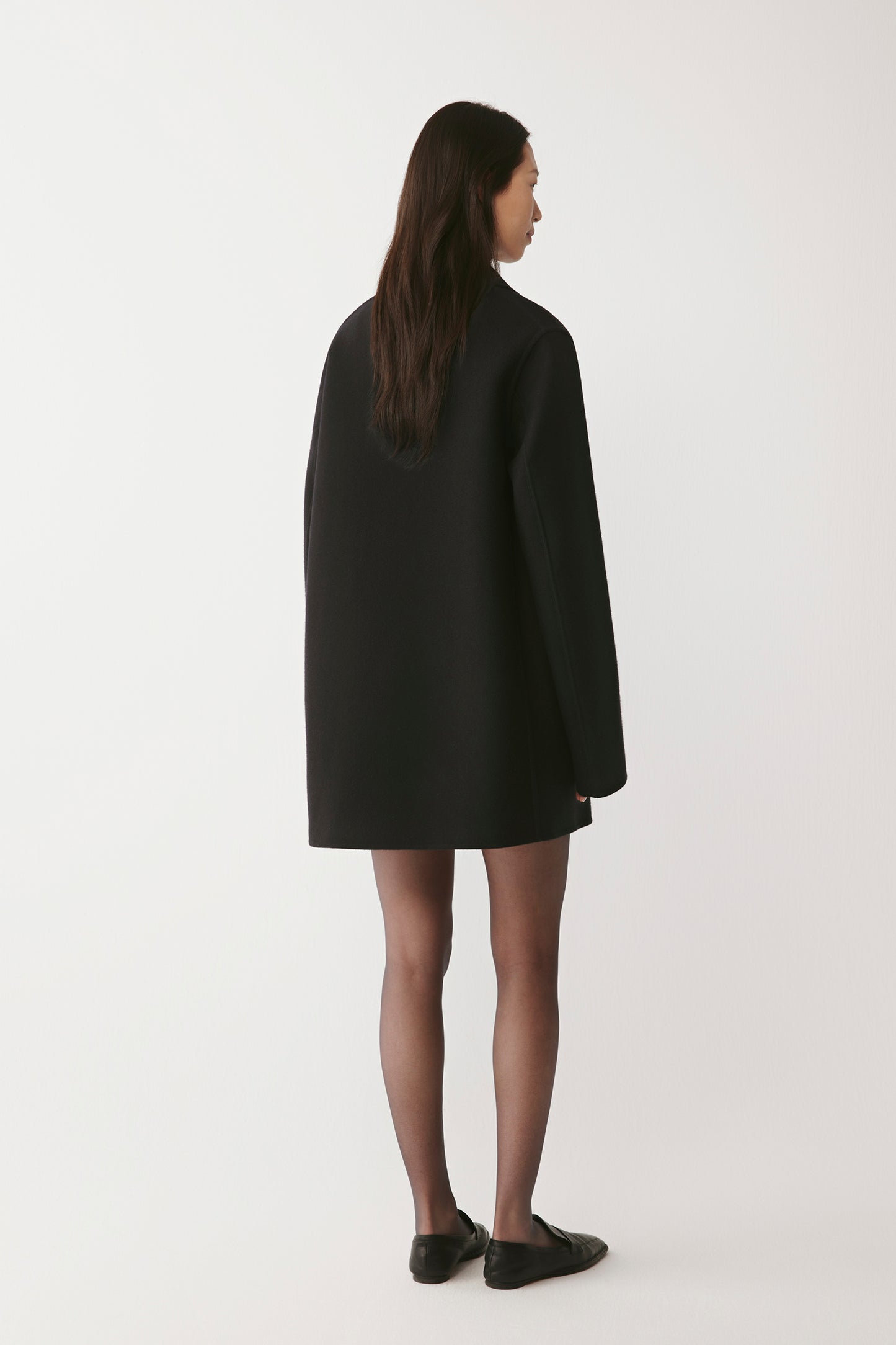 Back view of the black peacoat, highlighting the clean lines and classic tailoring.