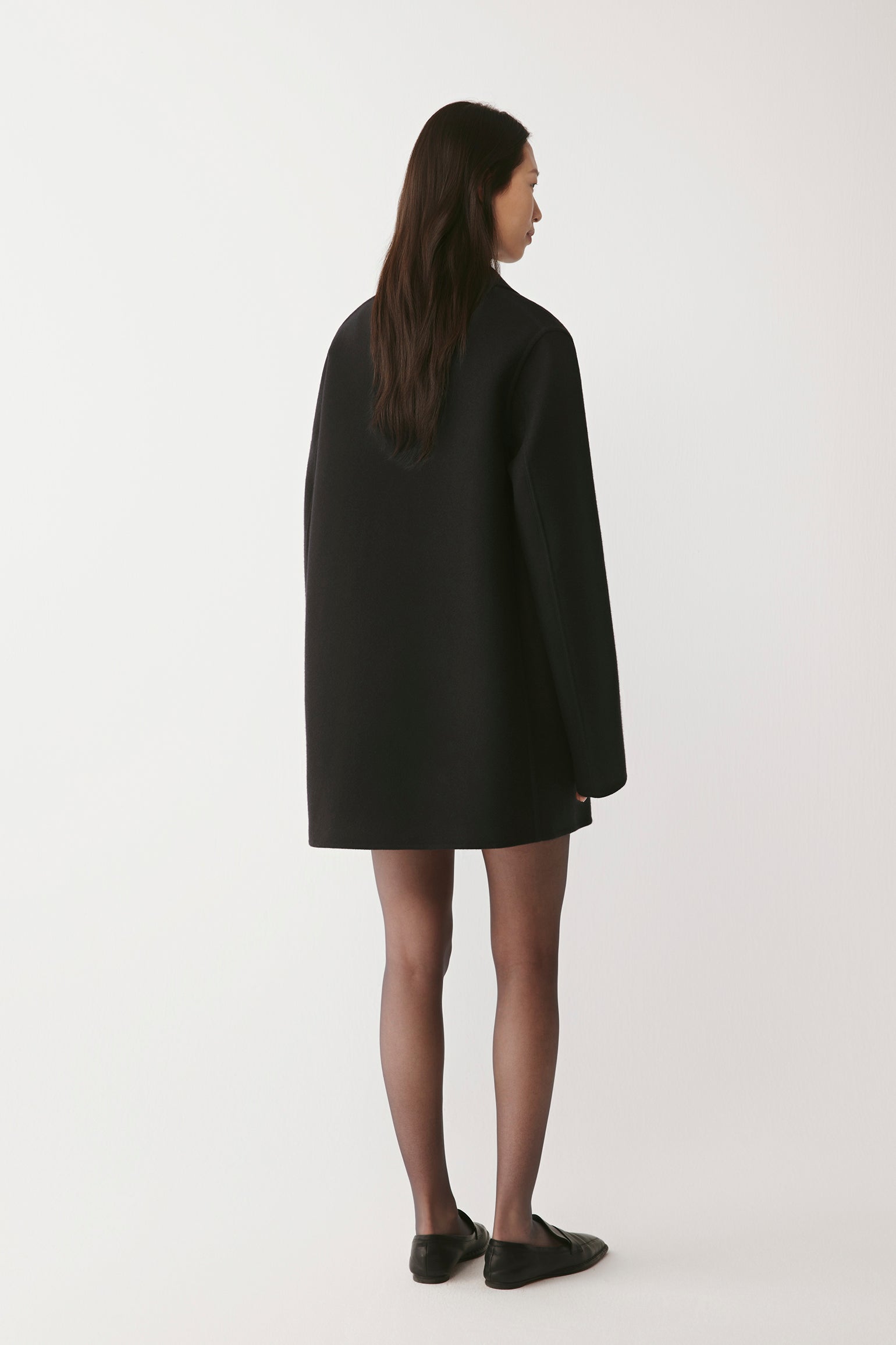 Back view of the black peacoat, highlighting the clean lines and classic tailoring.