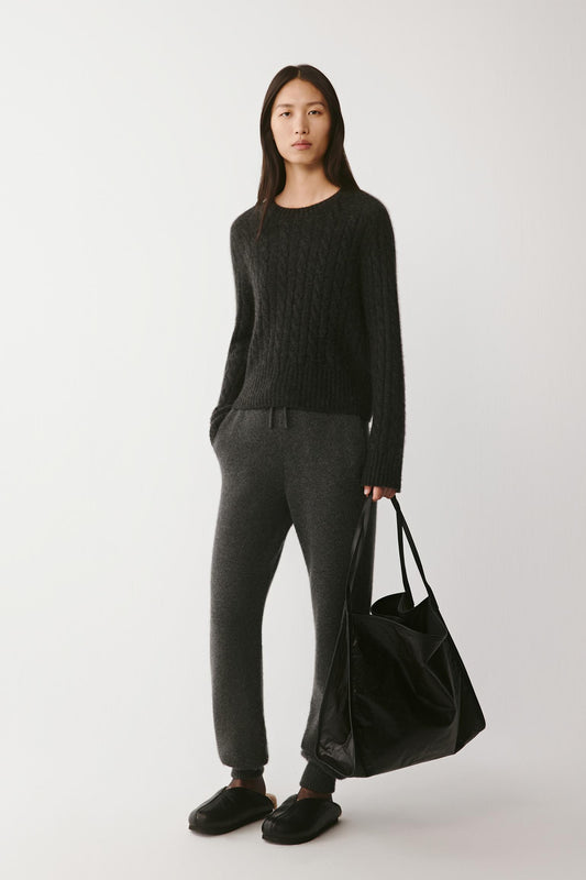 Full-length view of the model in black outfit holding the tote at her side, emphasizing the bag’s generous volume.