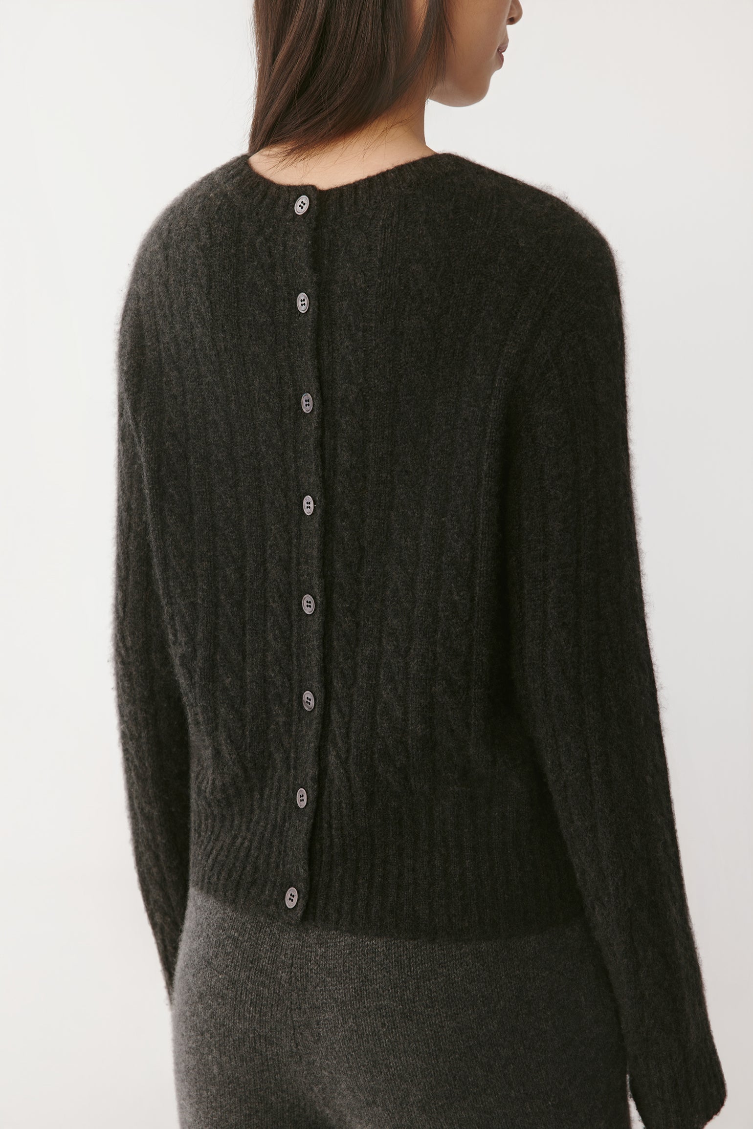 Close-up of the cable-knit texture, showing the fine natural fibres and ribbed neckline.