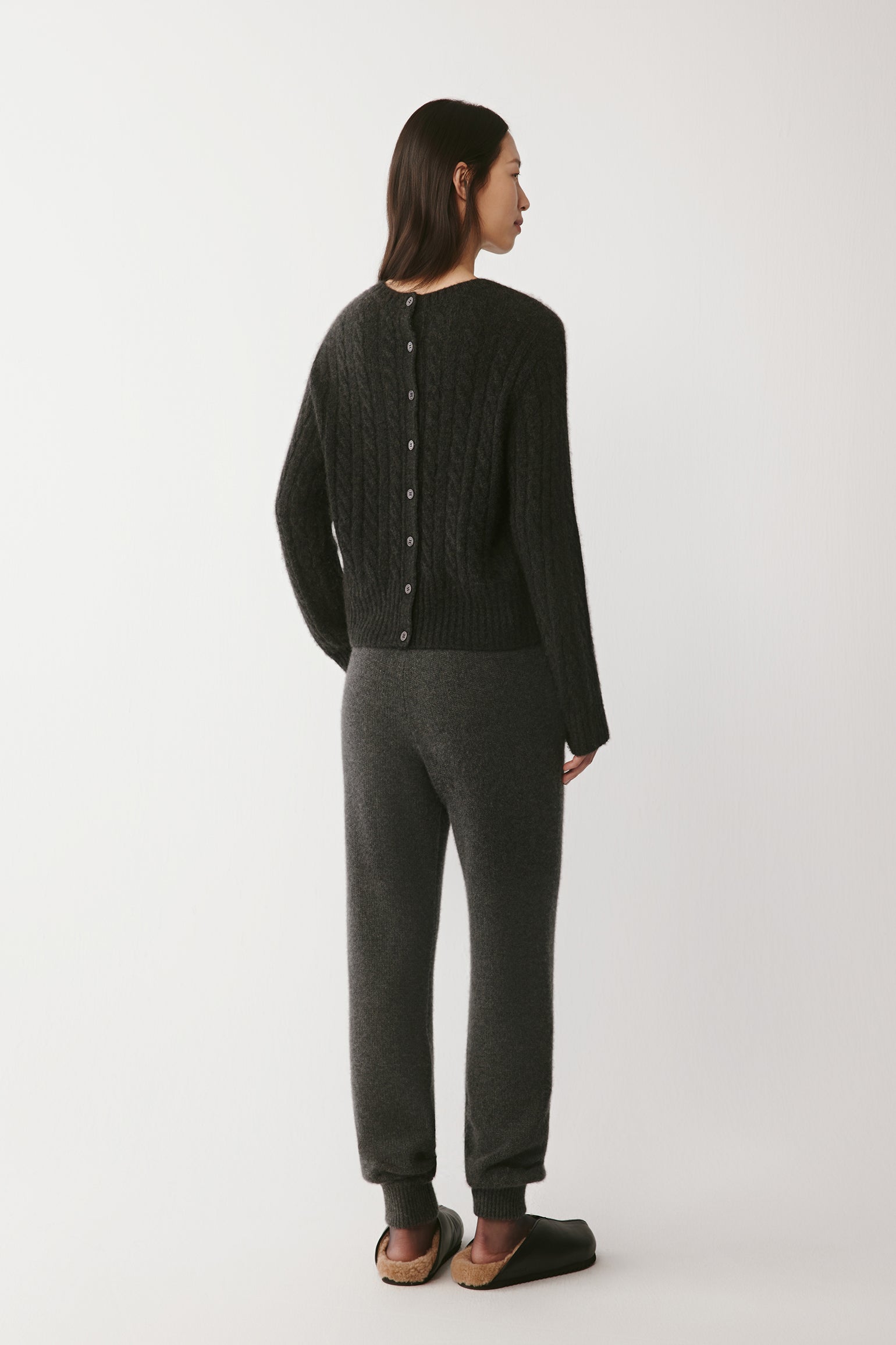 Back view of the grey pullover, highlighting the buttoned closure detail along the spine.