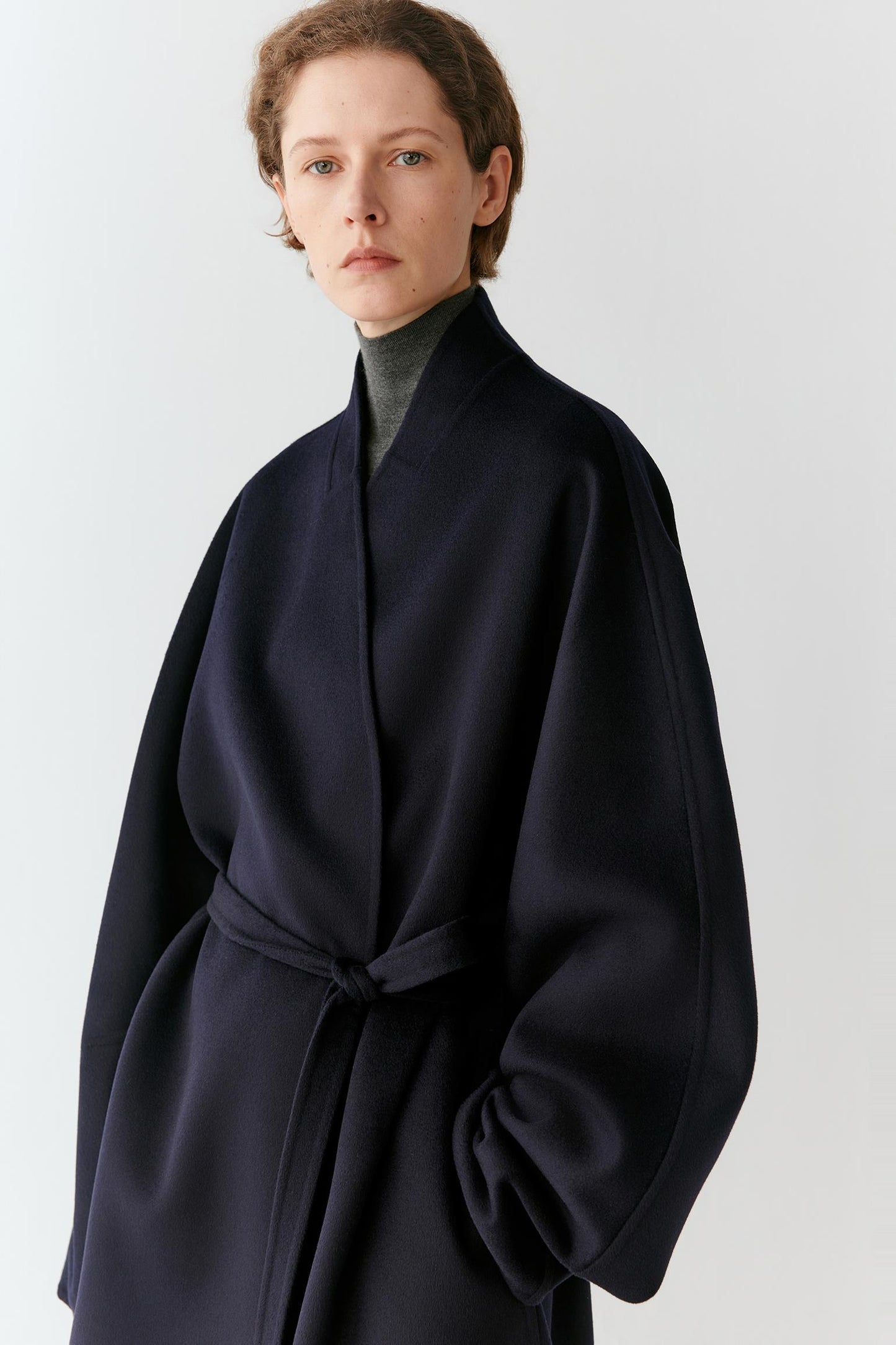 Three-quarter front view emphasizing the shawl collar, dropped shoulders and belted waist.