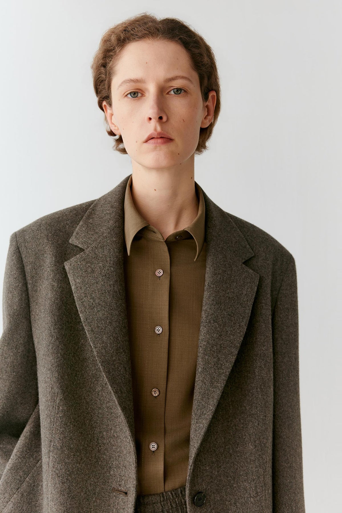 Close-up highlighting the notched lapels, chest welt pocket and visible tweed texture of the grey melange wool blazer.