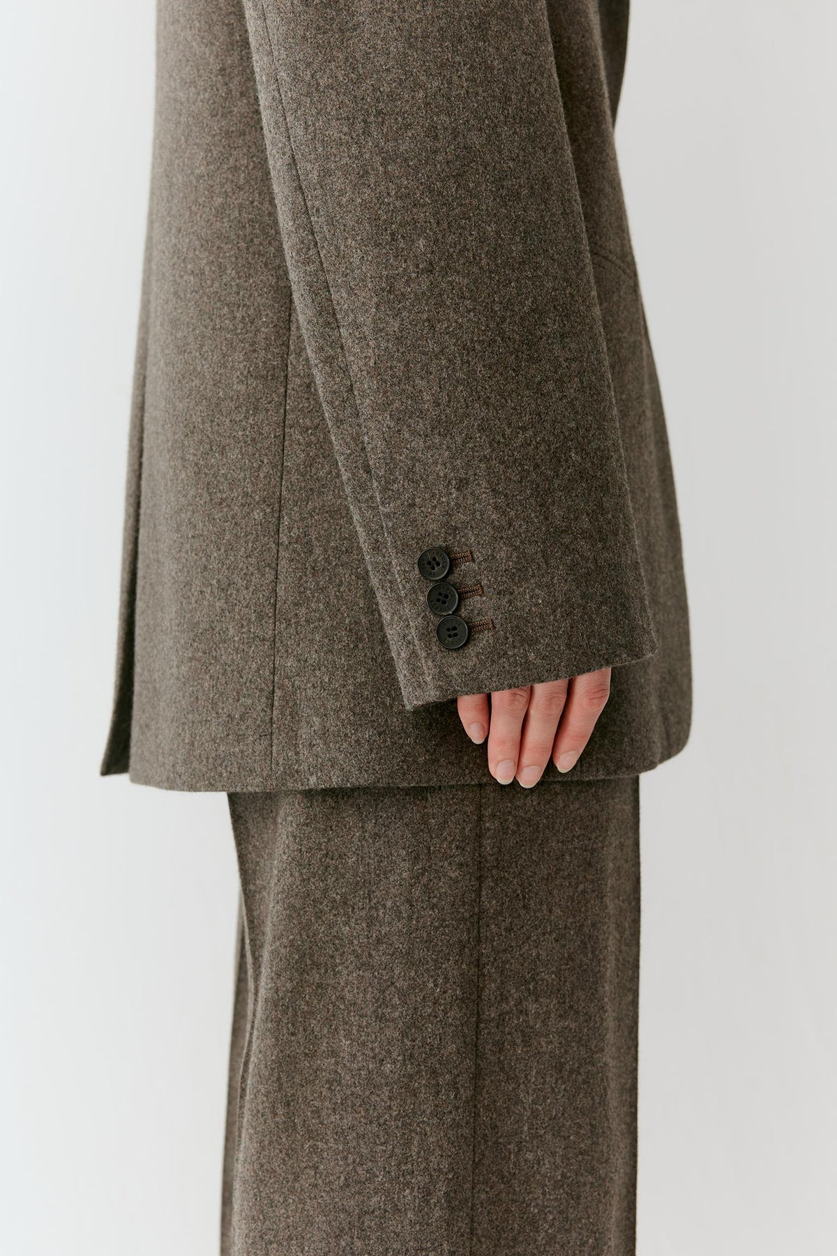 Close-up of the long sleeve and buttoned cuff, highlighting the textured tweed wool surface.