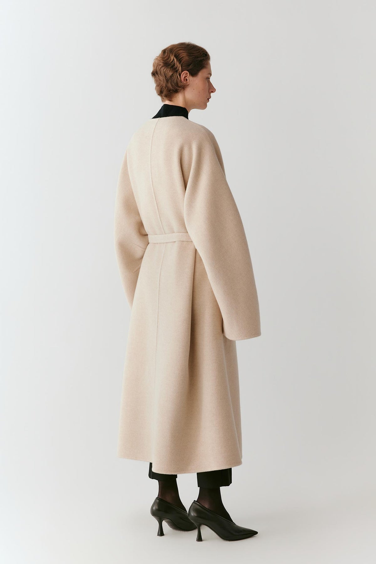 Back view showing the long silhouette and clean double-face construction of the beige melange wool and cashmere coat.