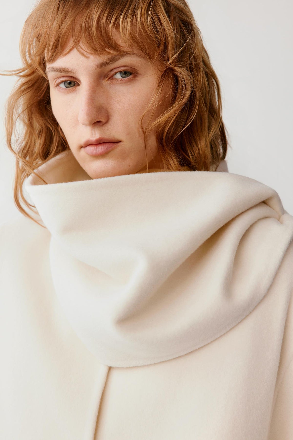 Close-up highlighting the folded stand collar and smooth ivory wool and cashmere surface.