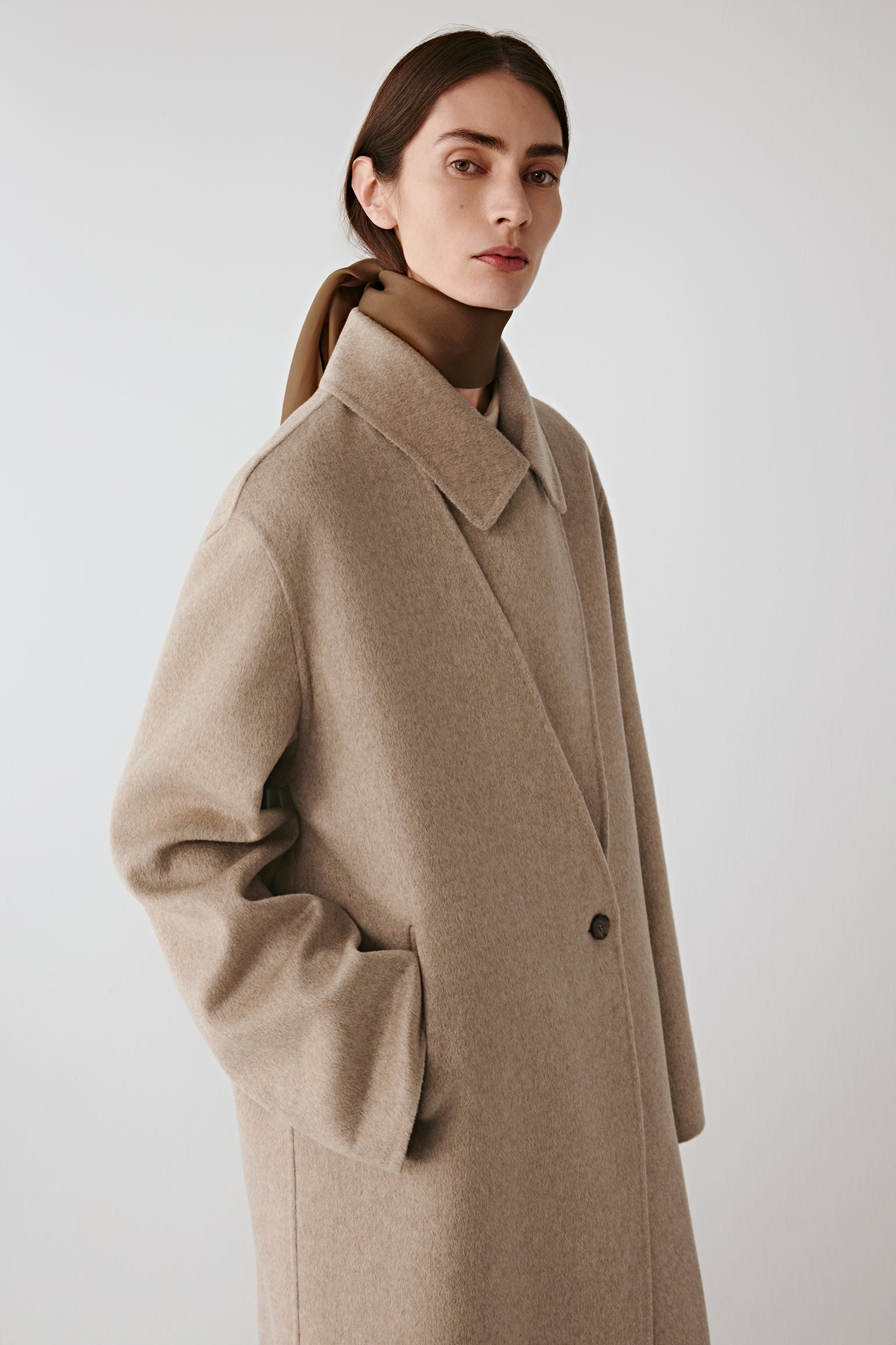 Three-quarter front view highlighting the long straight silhouette and single-button fastening.