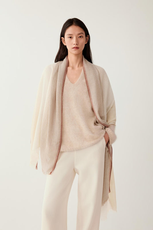 Full-length front view of an undyed cashmere scarf worn loosely over a light outfit, showing its length and soft drape.