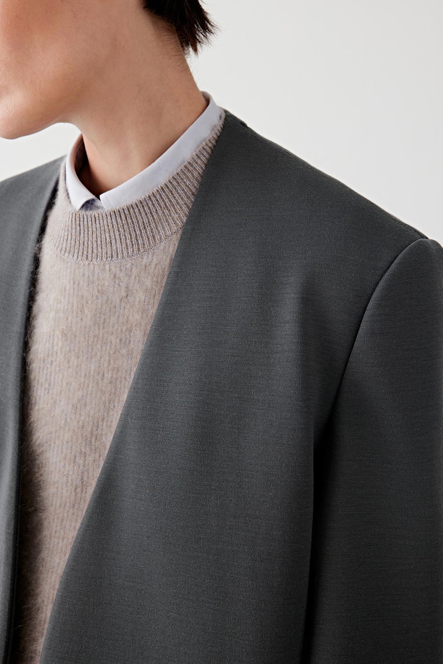Close-up of the collar and lapel, showing the dense, matte texture of the wool jersey.