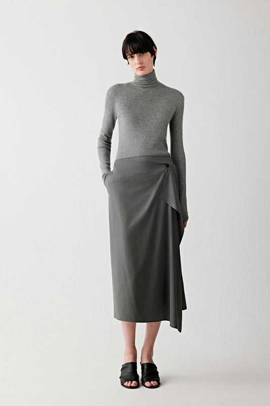 Full-length front view of a smoke grey worsted cashmere pullover with a fitted silhouette, long sleeves and high neckline, paired with a long skirt.