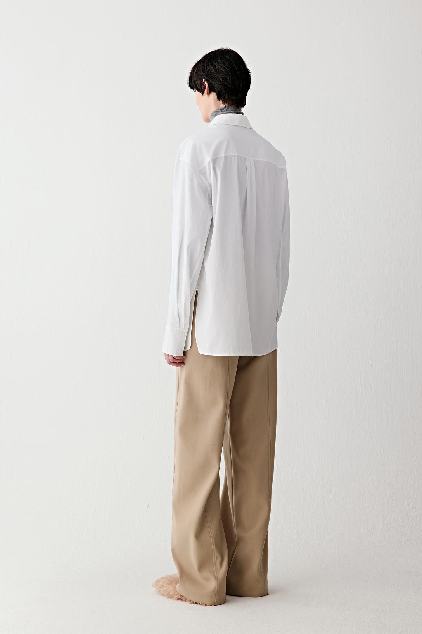 Back view of the white cotton shirt, highlighting the smooth back panel and straight hem.