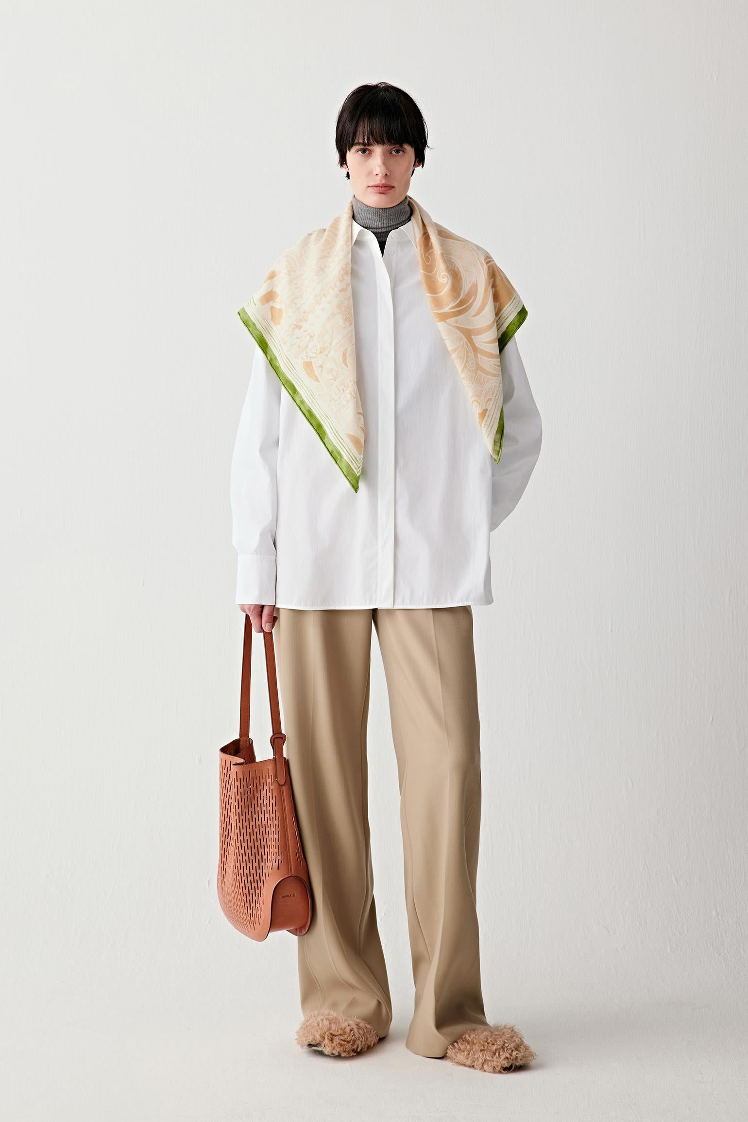 Full-length view showing the tan leather hobo bag styled with a light outfit, emphasizing the lightweight structure and relaxed volume.