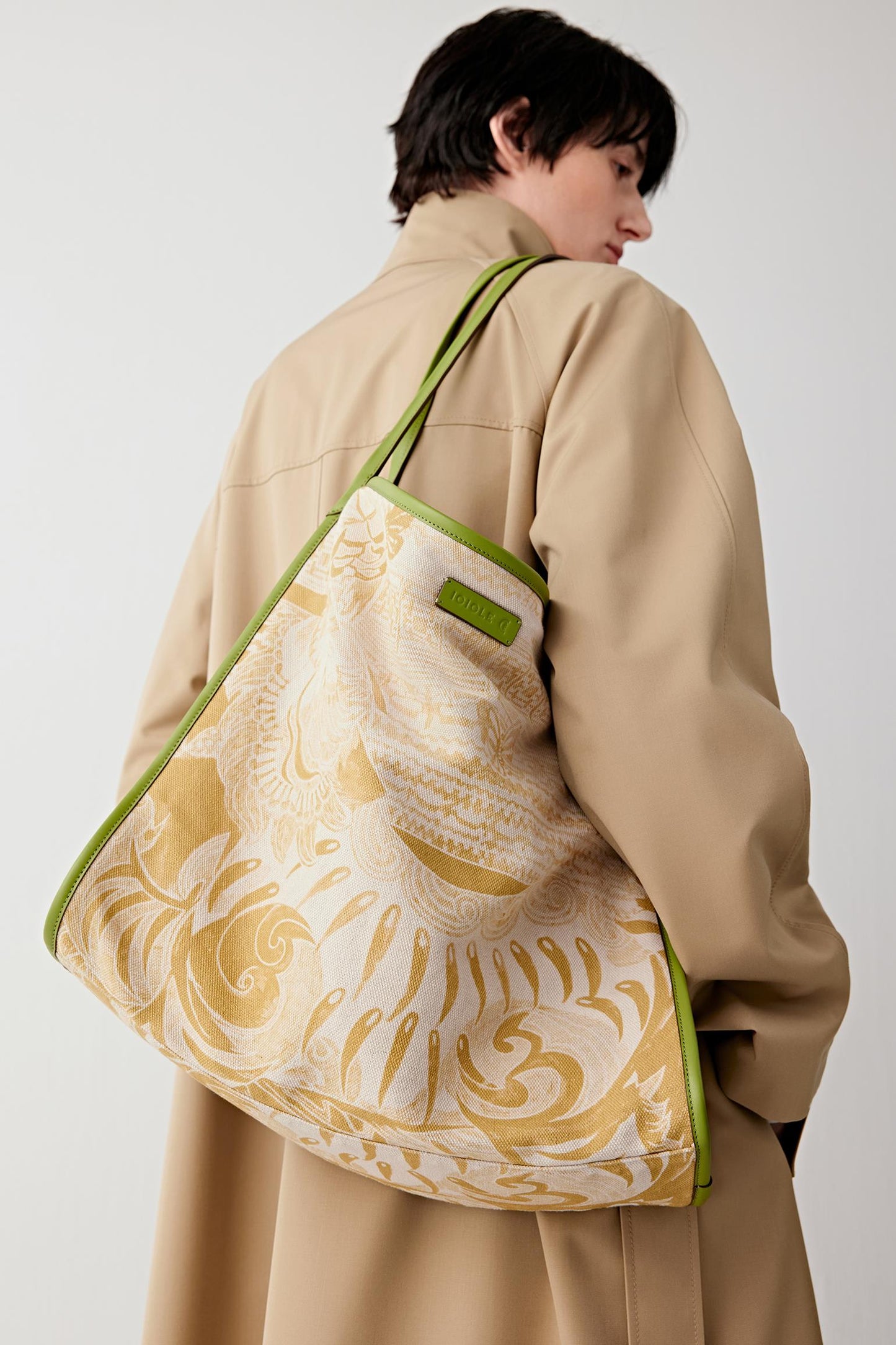 Woman wearing a large tote bag in linen and cotton with a beige base and yellow White Tiger motif, carried on the shoulder, back three-quarter view highlighting the soft structure and wide strap.