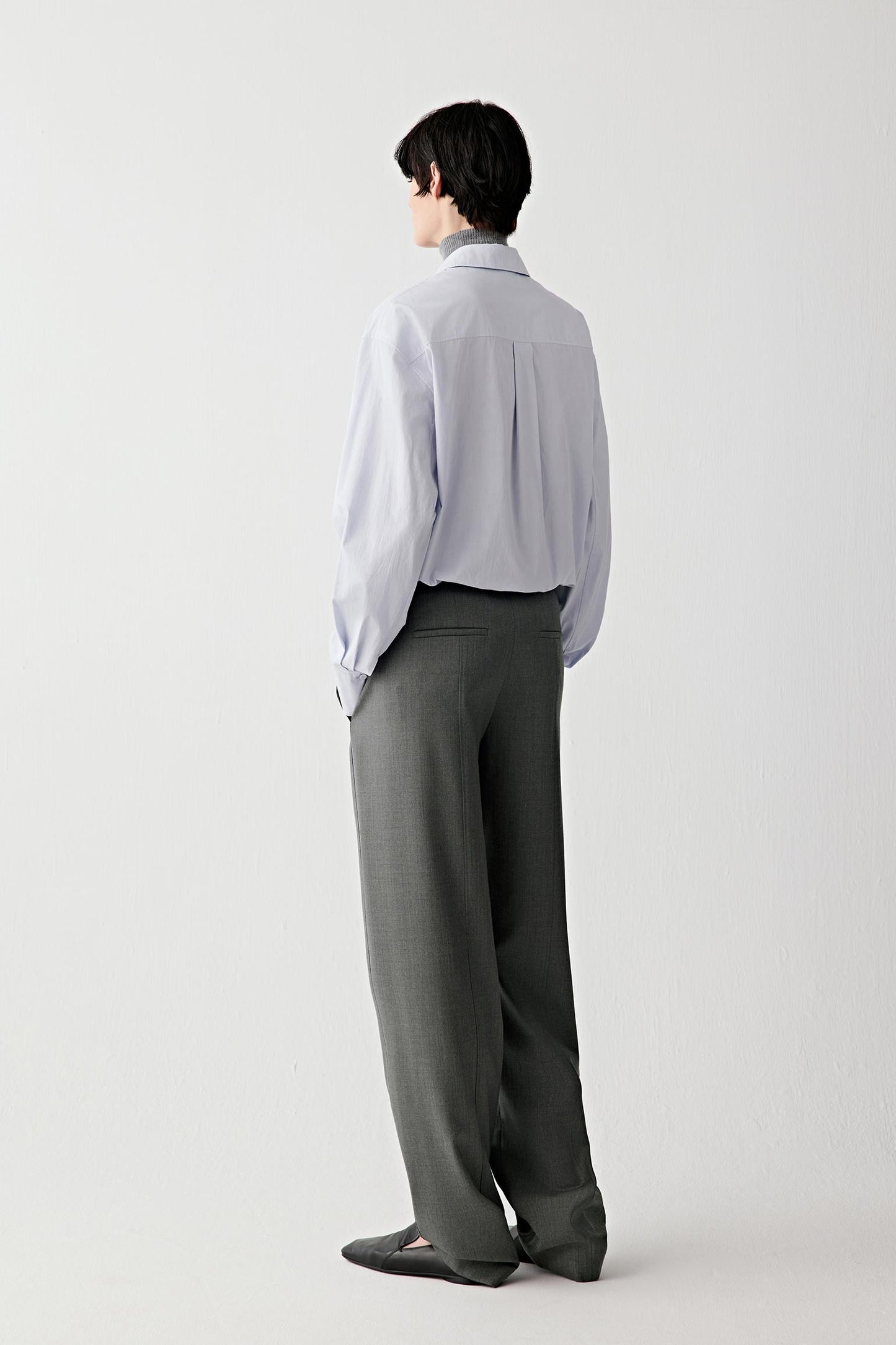 Back view of the light blue cotton shirt, showing clean construction and straight lines.
