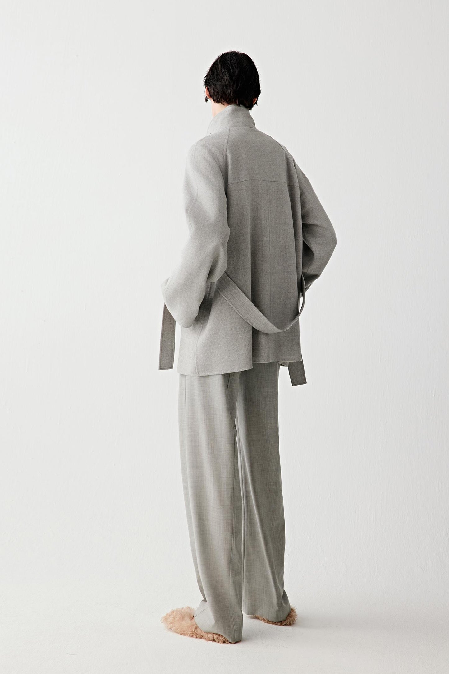 Back view showing the straight fall from shoulders to hem, clean back panel and belt tied at the waist, emphasizing the unstructured drape.