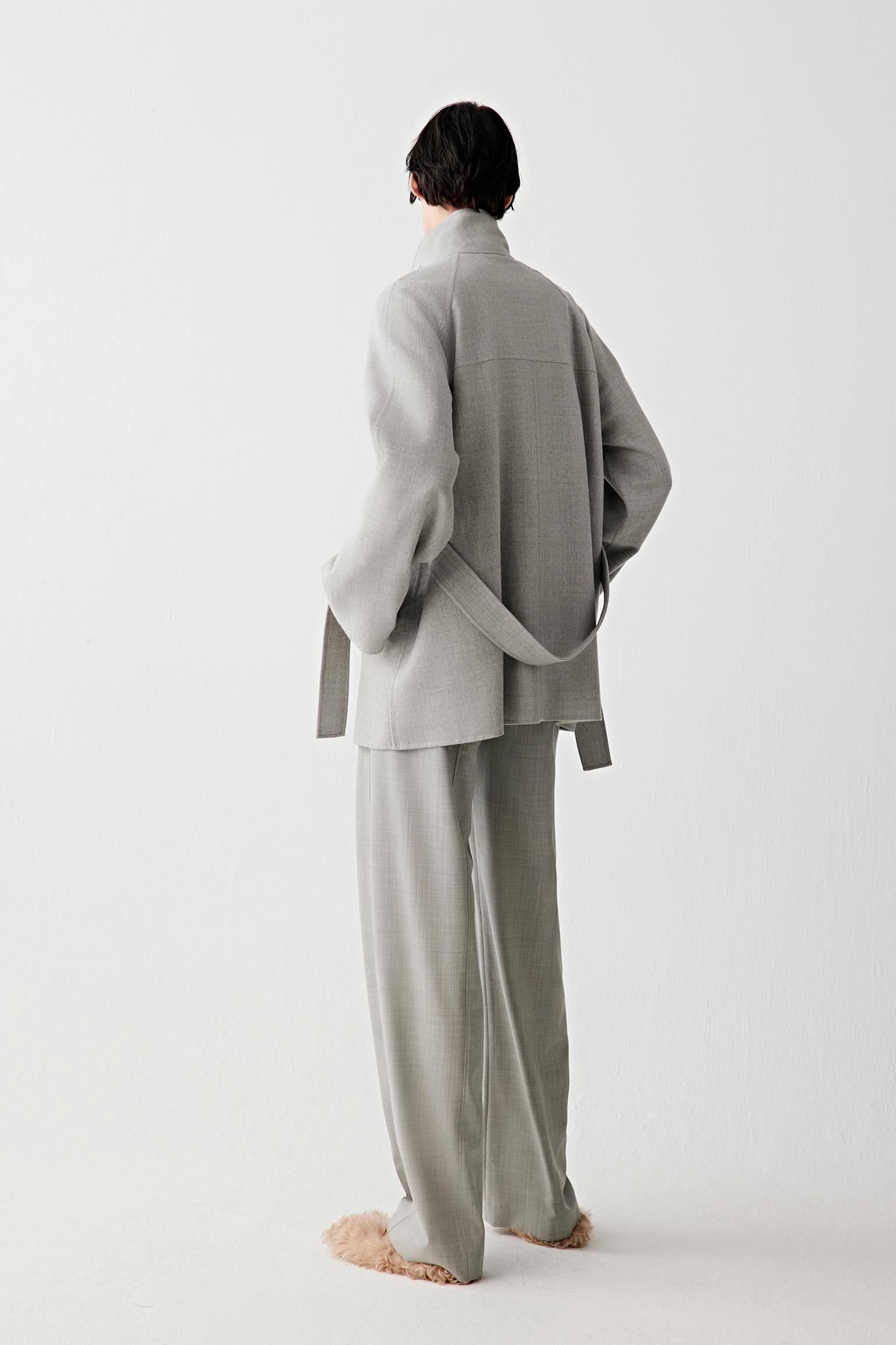 Back view showing the straight fall from shoulders to hem, clean back panel and belt tied at the waist, emphasizing the unstructured drape.