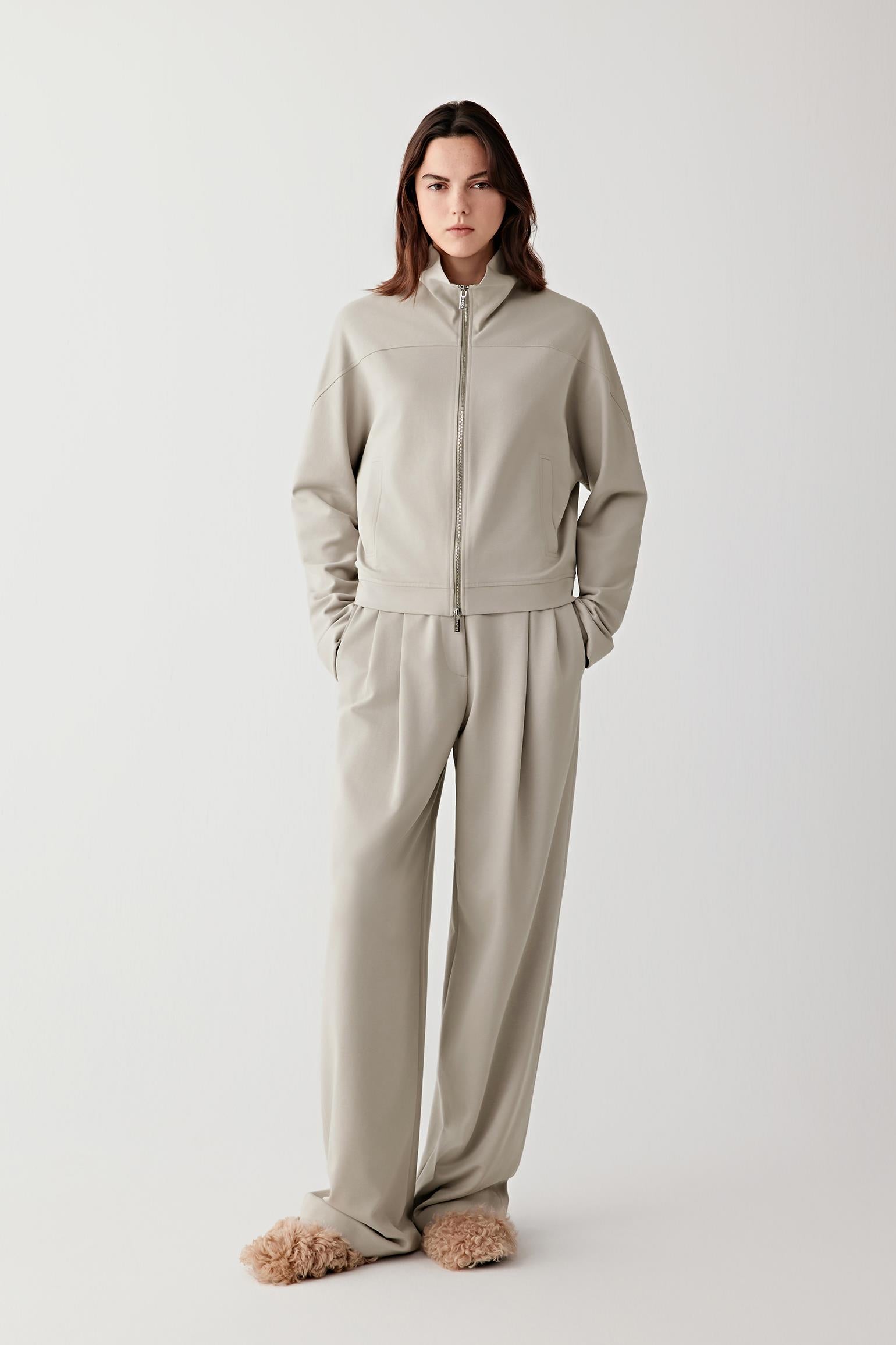 Full-length front view of a short cotton stretch jersey jacket in soft sage grey, worn with matching trousers.