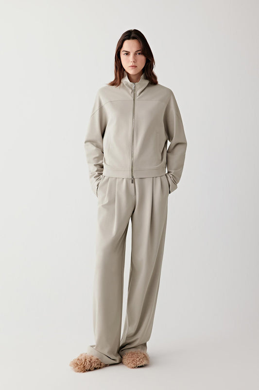Full-length front view of a short cotton stretch jersey jacket in soft sage grey, worn with matching trousers.