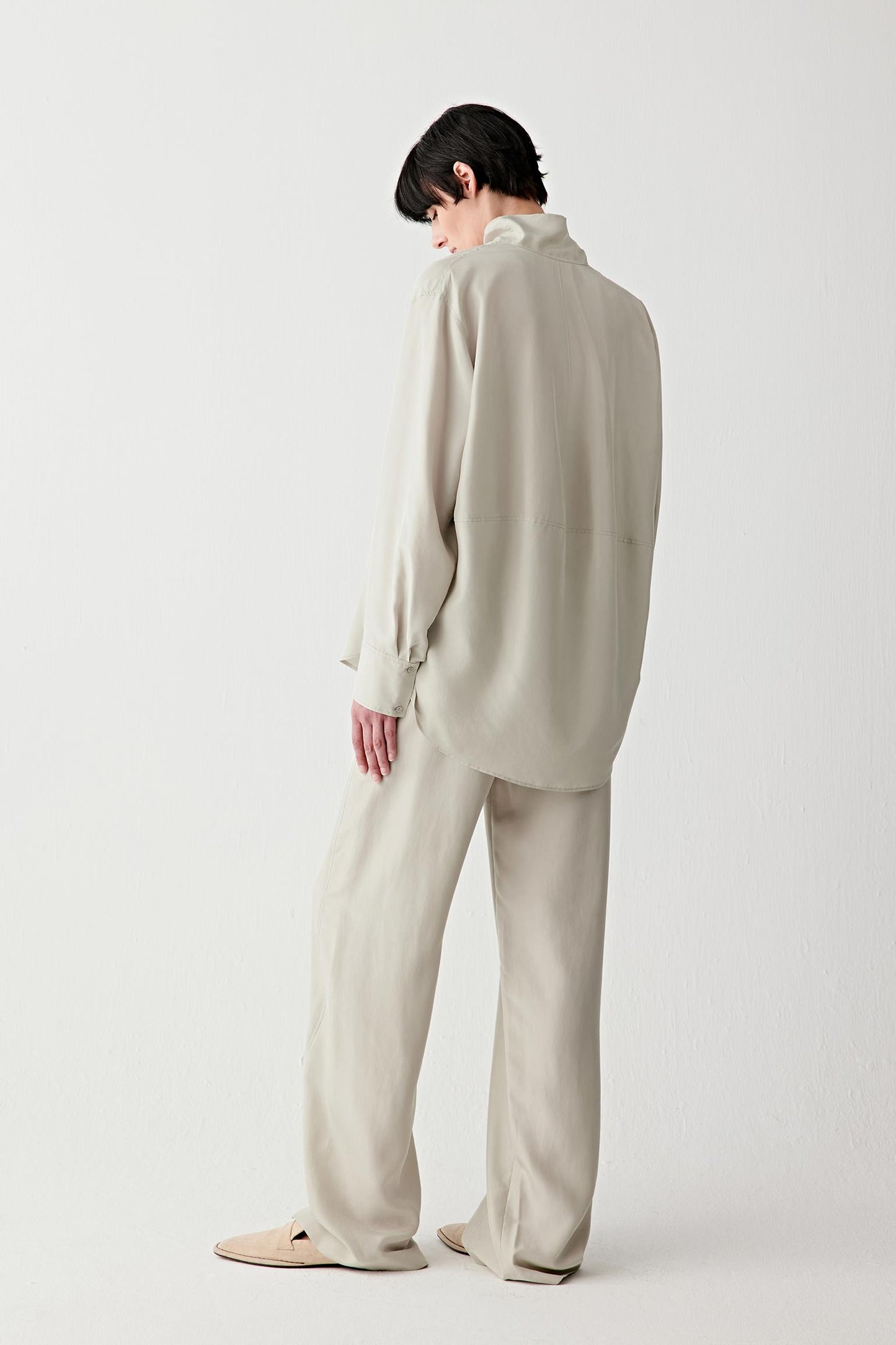 Full-length back view showing the rear silhouette, highlighting the straight cut, the fluid fall across the back and the soft, natural movement of the silk fabric