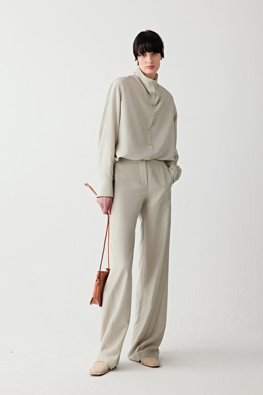 Full-length front view showing the shirt styled with matching trousers, emphasizing the relaxed silhouette, the way the fabric falls loosely from the shoulders and the clean, continuous line from collar to hem