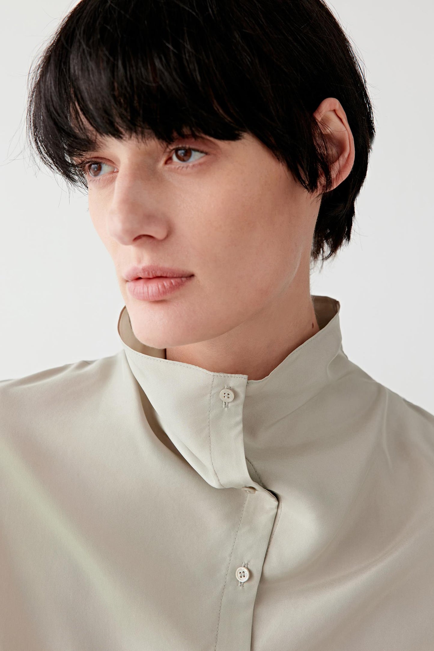 Close-up of the neckline and collar, focusing on the stand collar construction, button placket and the smooth, slightly lustrous surface characteristic of silk habotai