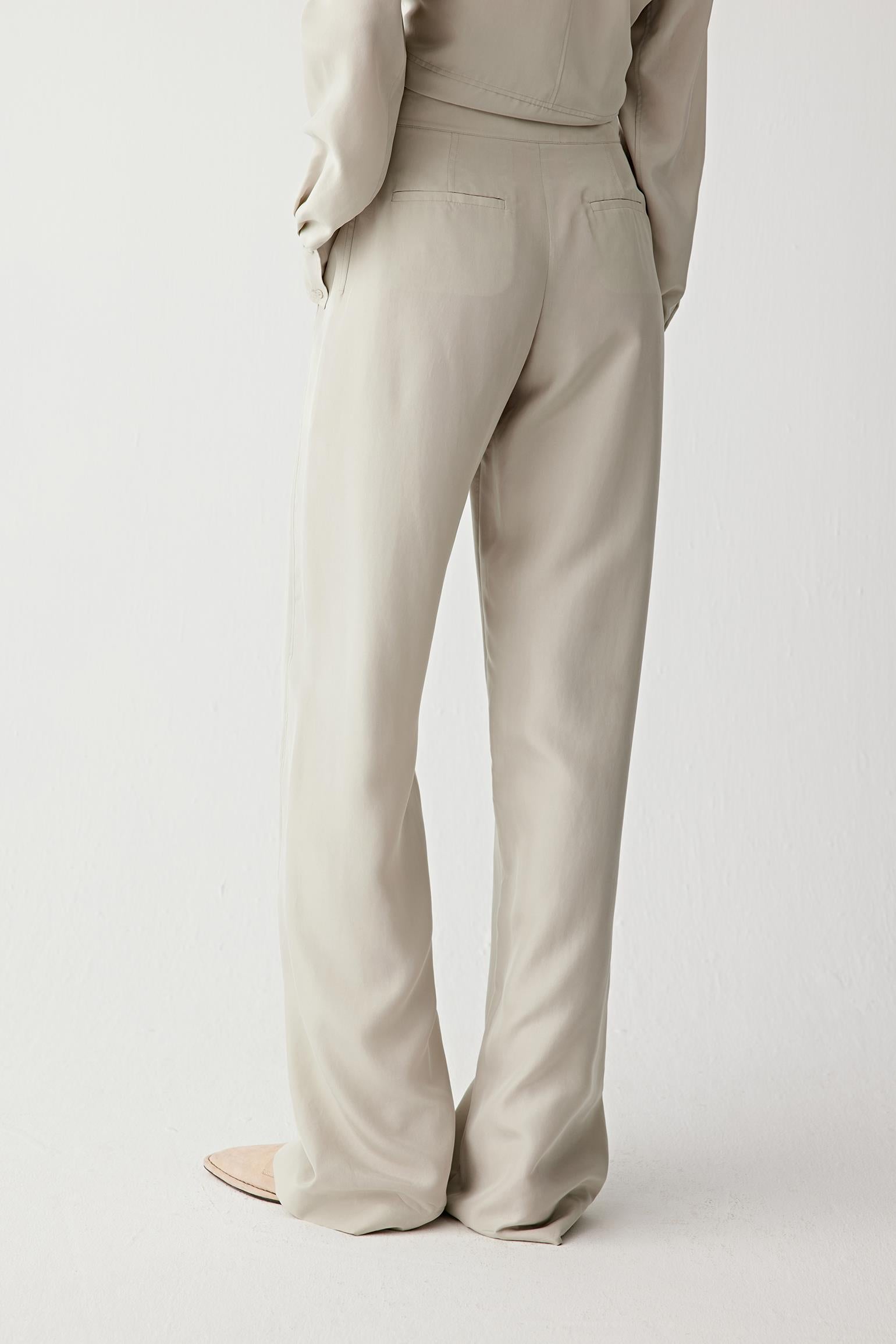 Full-length side view showing the trousers in profile, highlighting the fluid movement of the fabric, the relaxed fit through the leg and the continuous line from waistband to hem