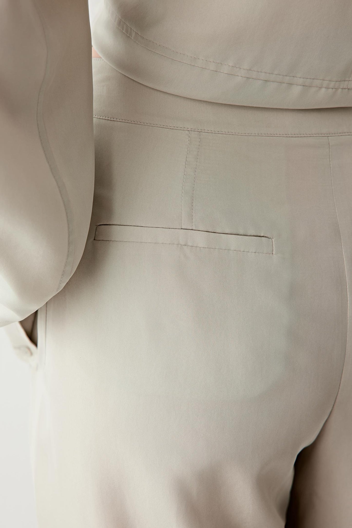 Close-up of the hip and upper thigh area, focusing on the fabric surface, showing the smooth texture, soft sheen and the way the material falls without stiffness