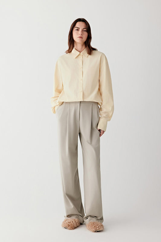 Full-length front view of sage grey cotton stretch jersey trousers with a relaxed straight-leg cut and elasticated waistband, worn with a light knit top.