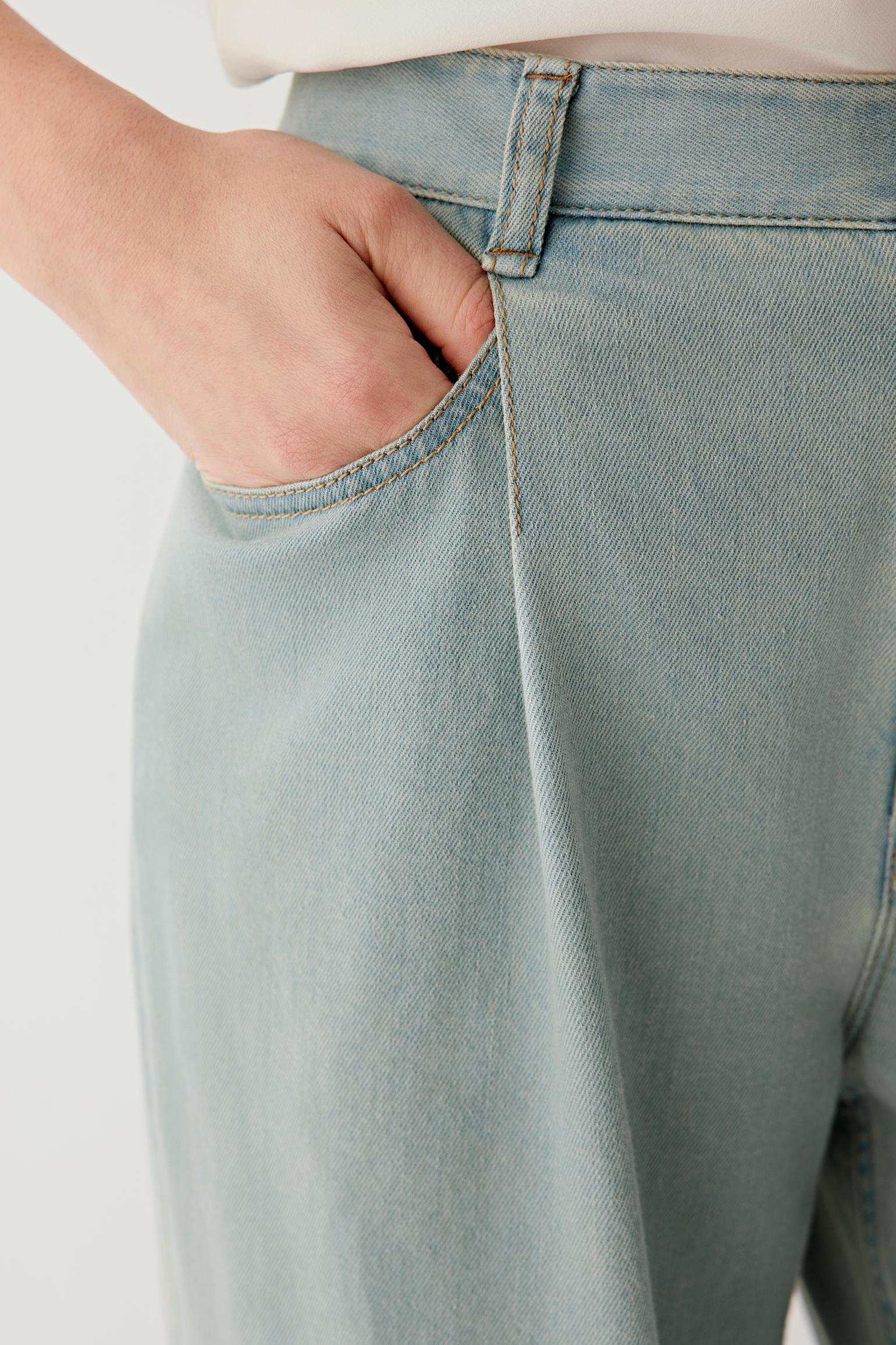 Close-up of the hip and front pocket area showing the denim’s lightly washed finish, visible stitching lines, pocket construction and soft surface with a fine, even grain