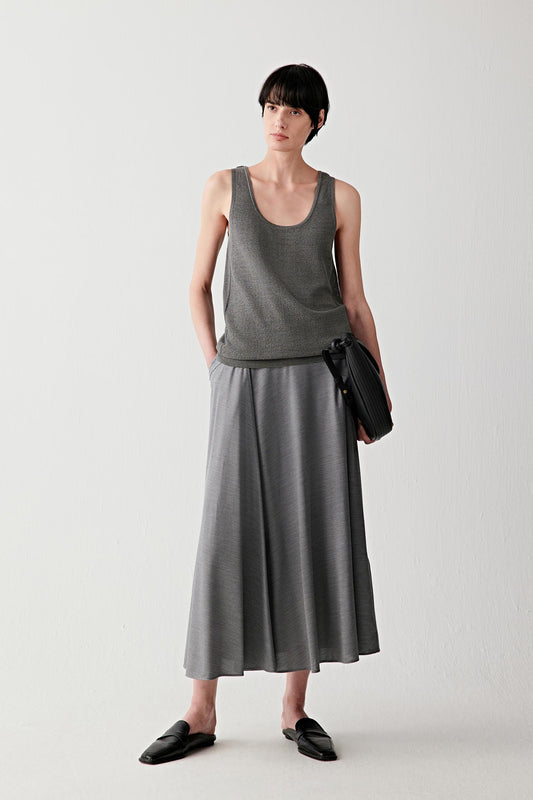 Full-length front view of a woman wearing a dark grey melange skirt in spun silk stretch jersey, highlighting the fluid drape, soft matte surface and elongated silhouette