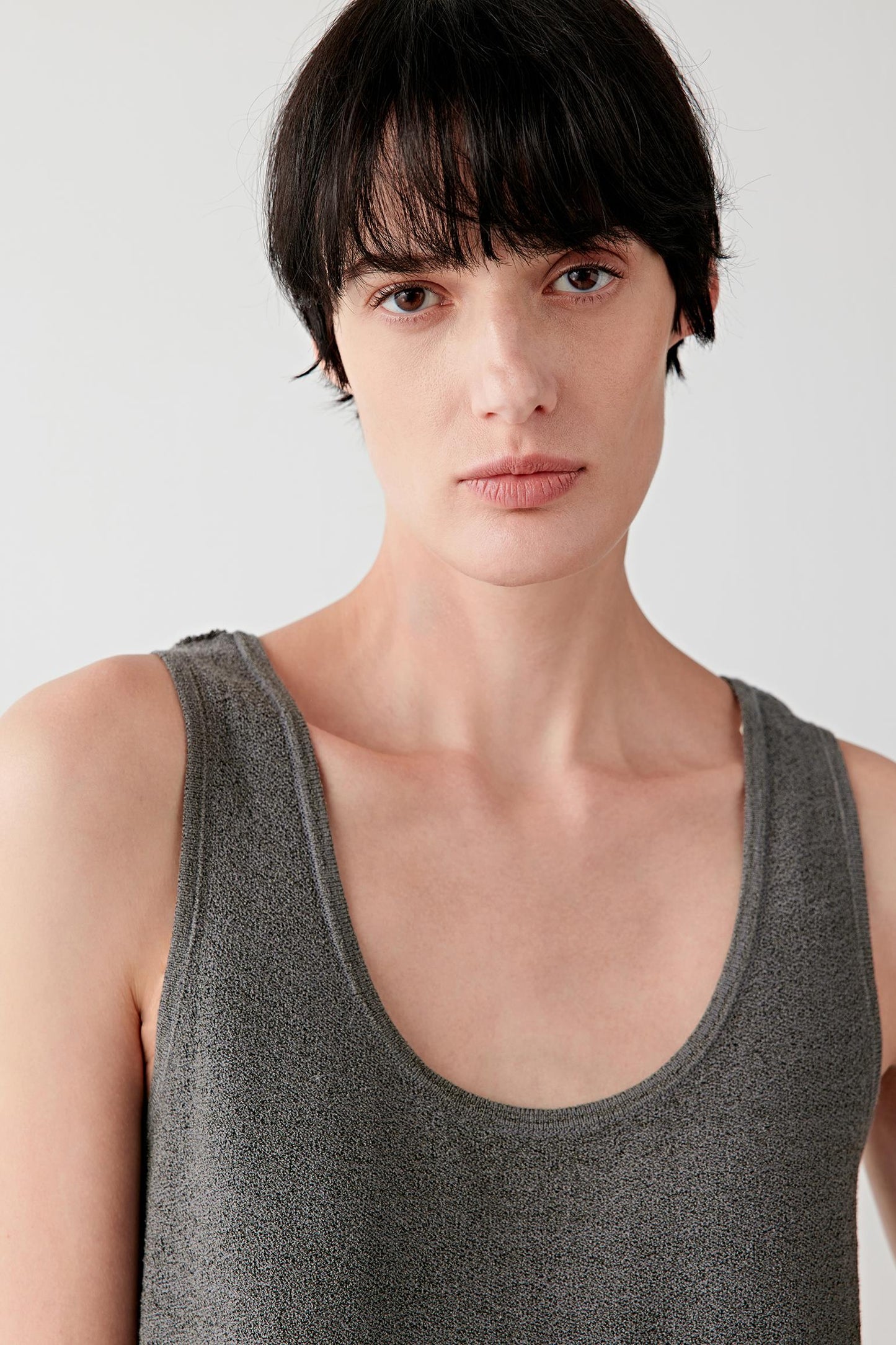 Close-up portrait focusing on the neckline and upper knit construction, detailing the lightly textured open knit surface and matte finish