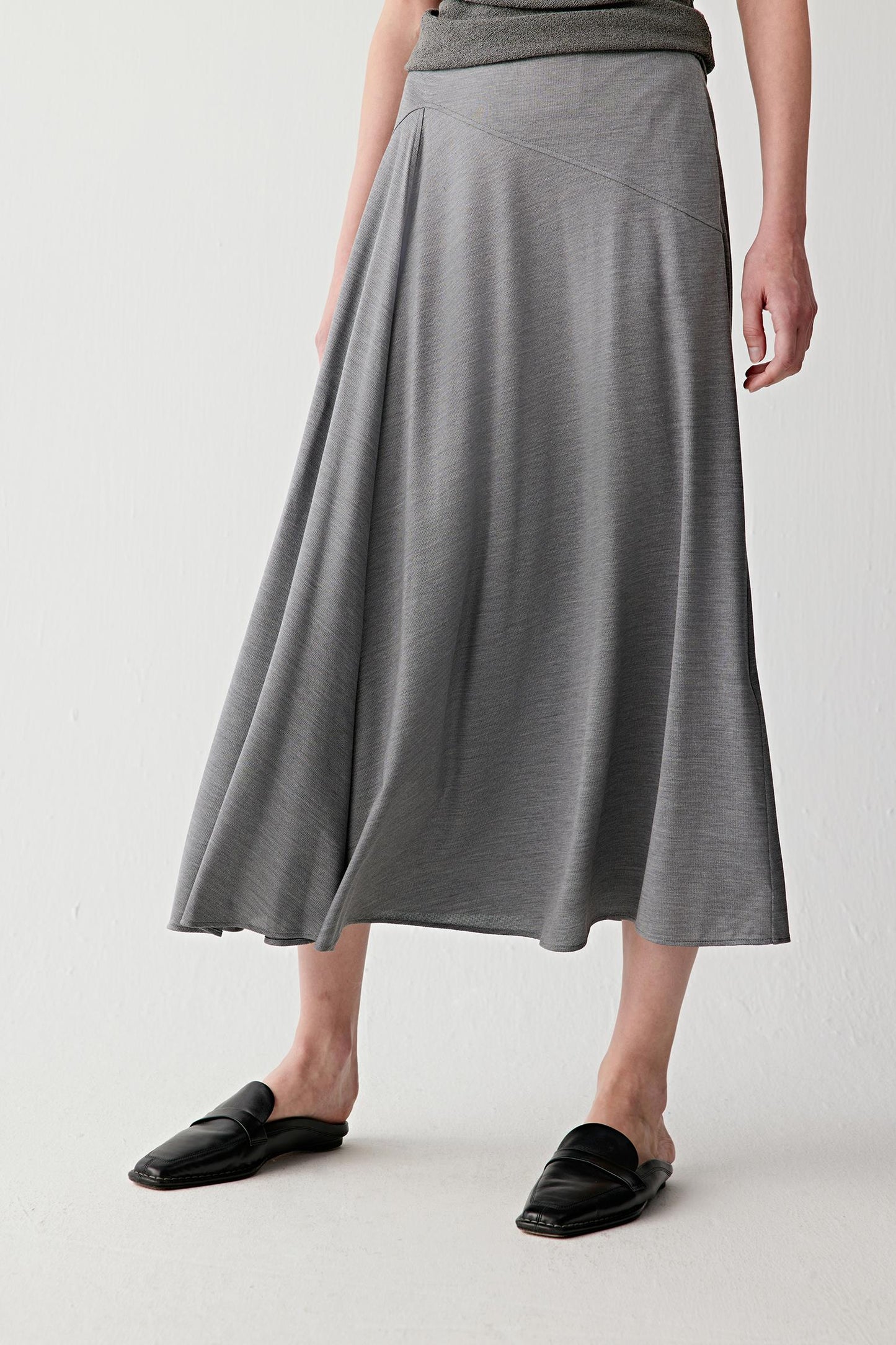 Front or three-quarter view emphasizing the fitted waistband and softly flared shape, showing the fluid movement of the stretch jersey construction