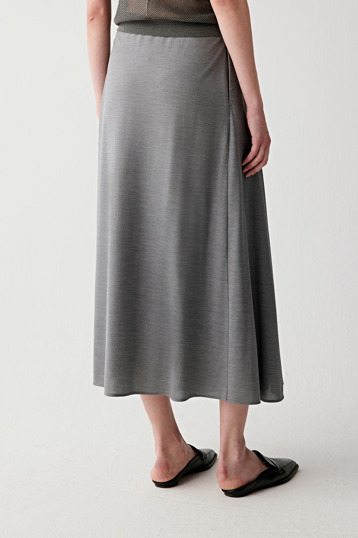 Full-length side or back view highlighting the panelled construction and soft drape through the skirt