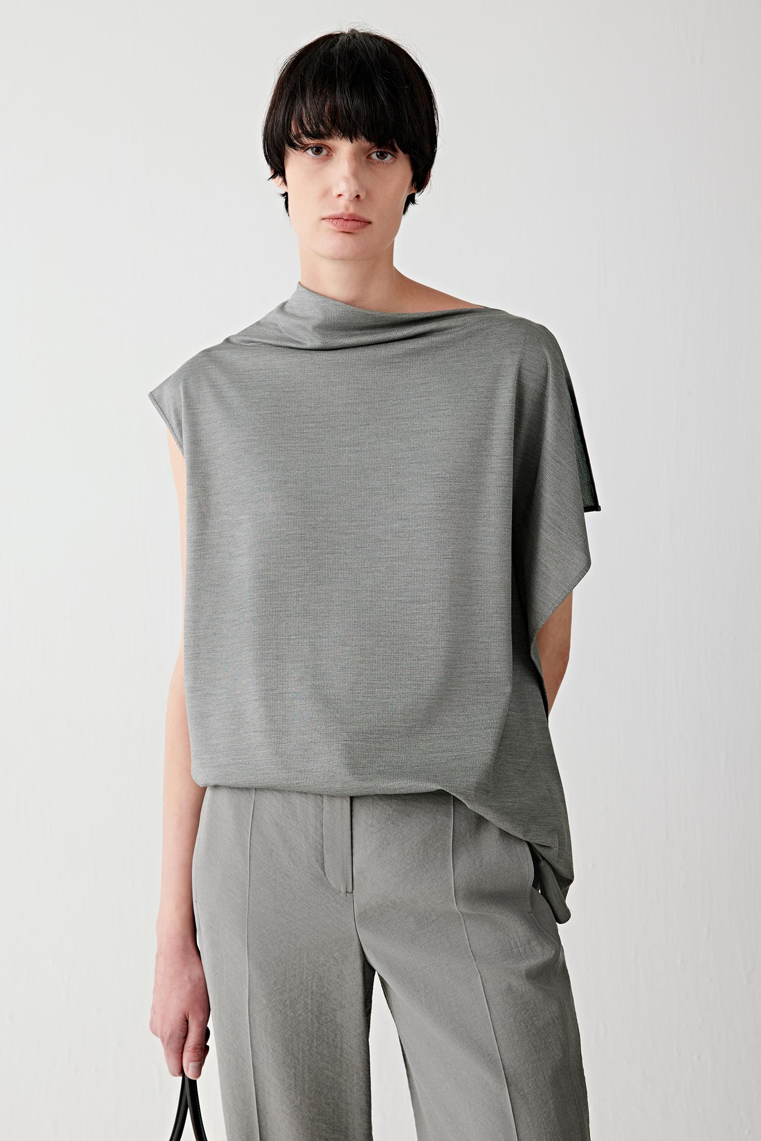 Front view of a woman wearing a dark grey mélange blouse in spun silk stretch jersey, highlighting the smooth matte surface, fluid drape and softly structured jersey construction. The mélange shade introduces subtle tonal variation across the surface.