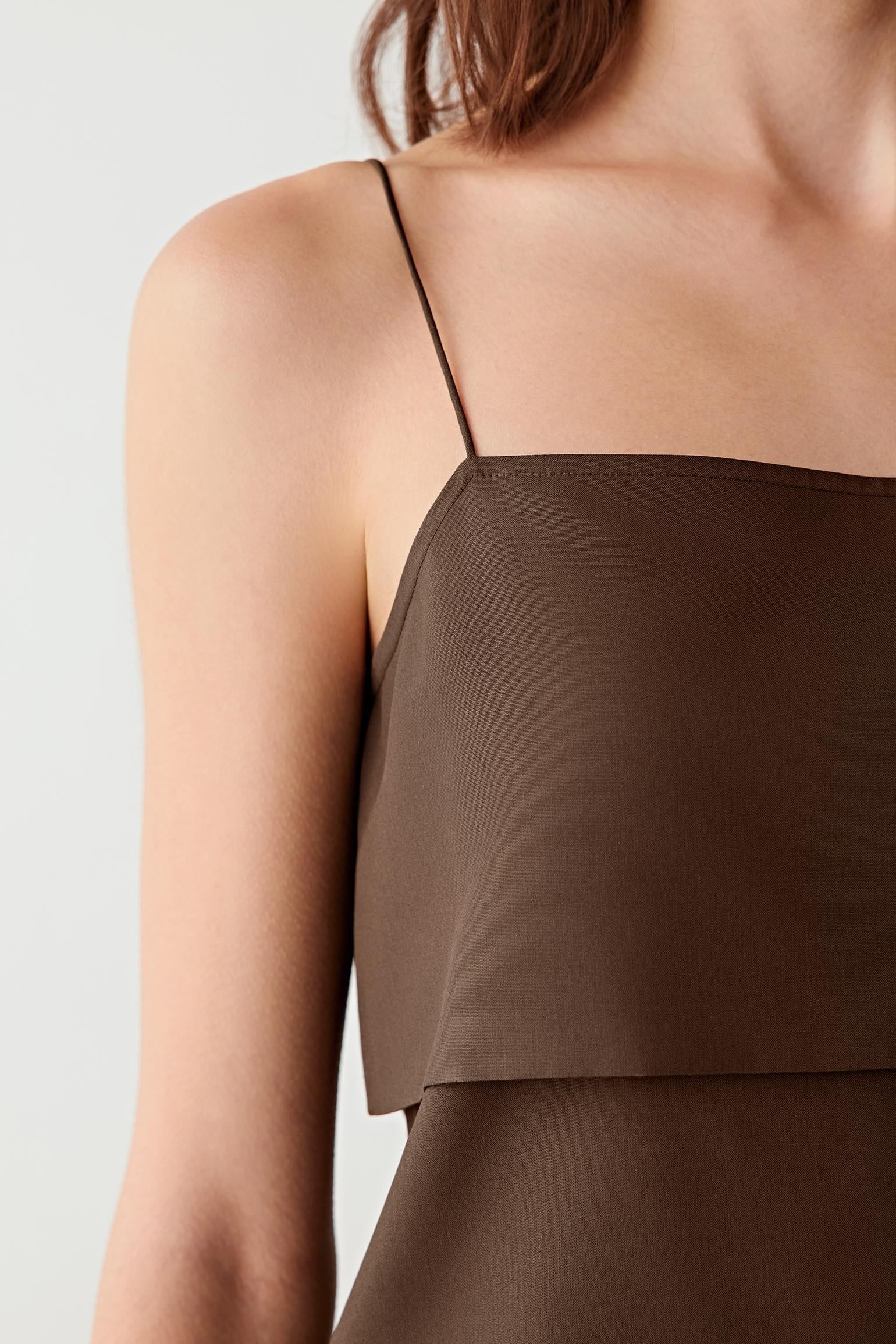 Close-up of fabric and construction detailing showing the layered panel structure, fine stitching and compact weave. The image highlights the smooth hand of the fabric, the fluidity of the drape and the softly reflective surface characteristic of spun silk poplin.