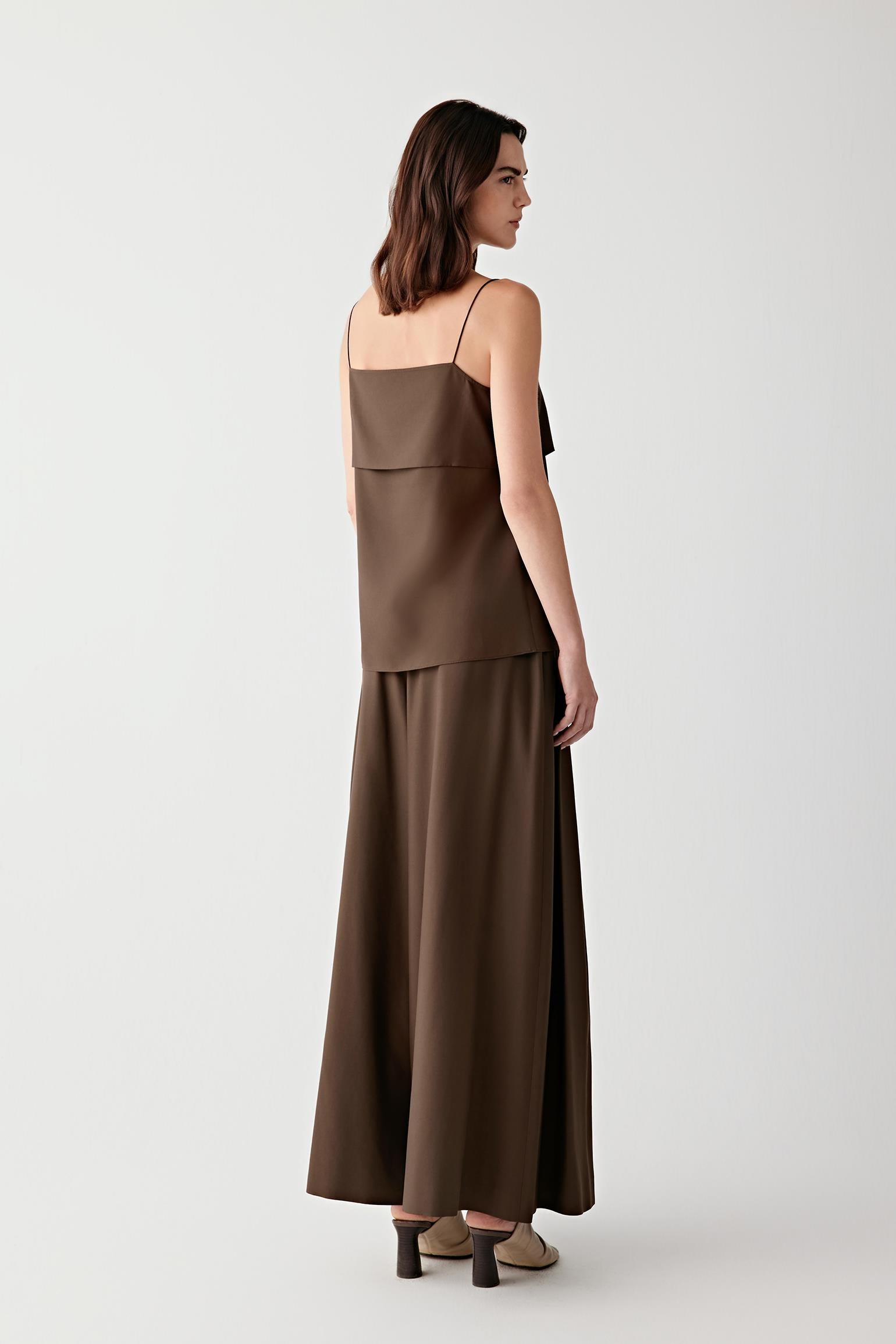 Side view highlighting the lightweight structure and vertical drape of the spun silk poplin. The fabric falls softly away from the body, revealing the balanced proportions and fluid movement of the silhouette.