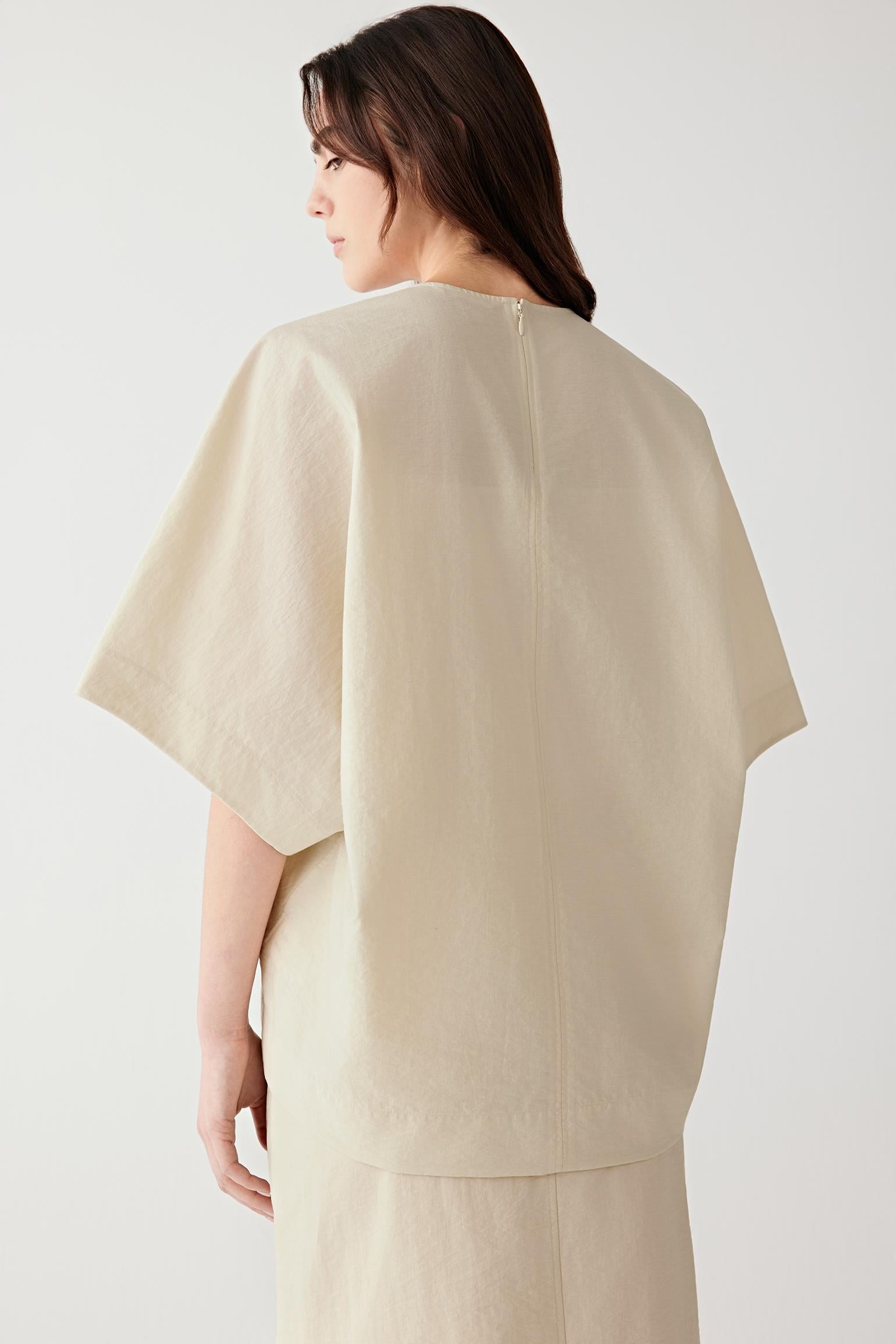 Close-up portrait focusing on the round neckline and upper construction, detailing the crinkled texture and matte finish of the poplin surface