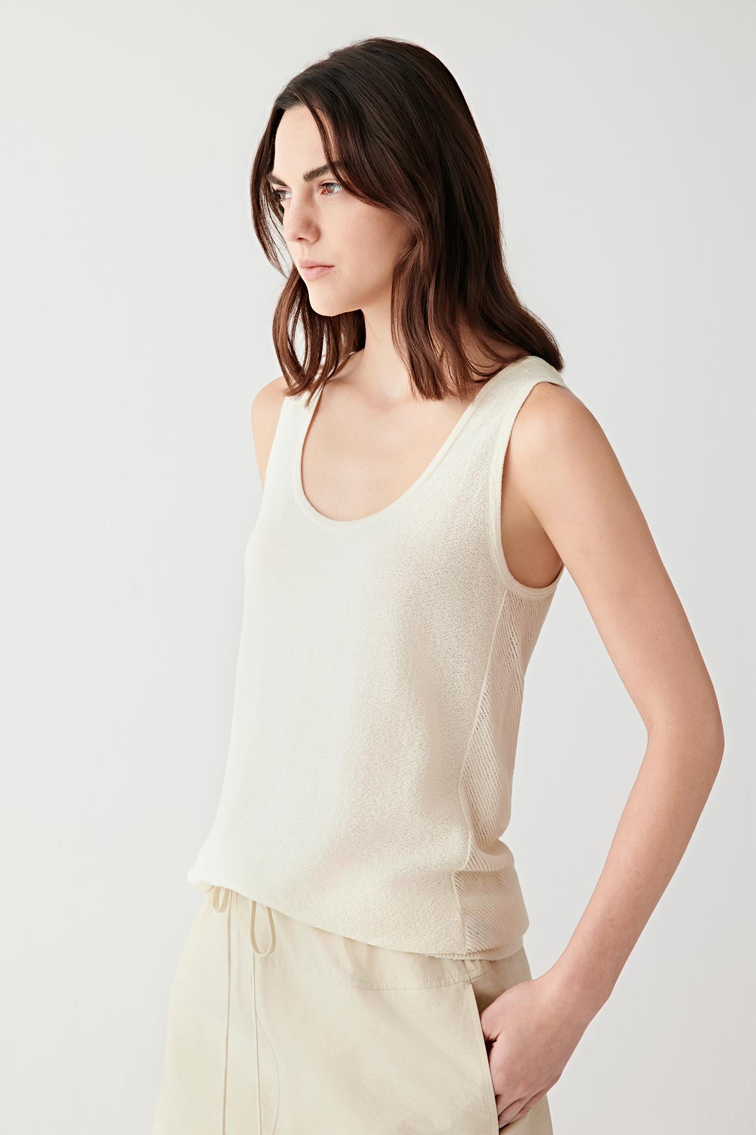 Close-up portrait focusing on the neckline and upper knit texture, detailing the fine openwork structure and softly sheer surface