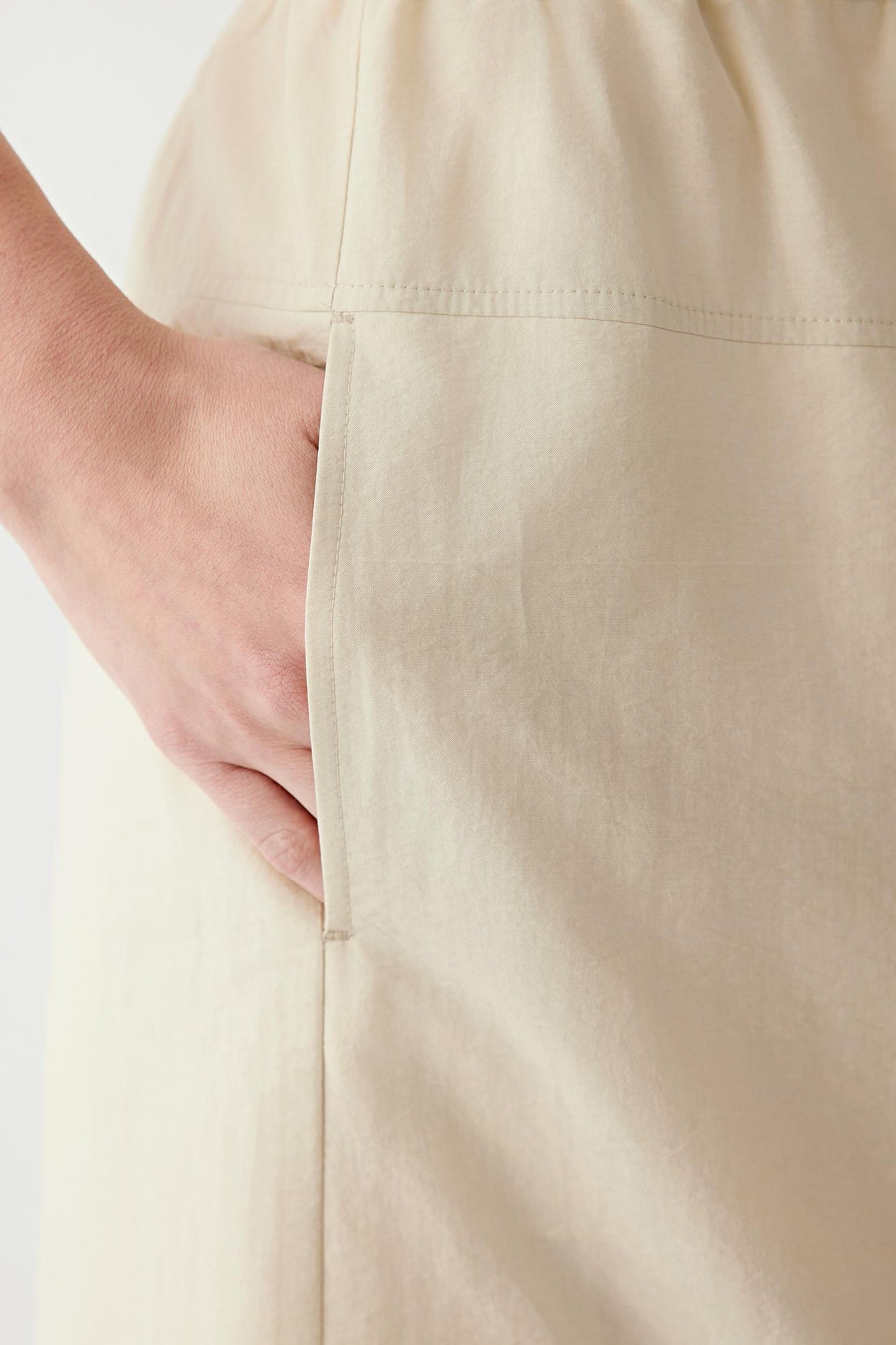 Close-up of the side pocket and surrounding fabric, showcasing the softly irregular crinkled surface, lightweight weave and matte finish. The image highlights the subtle texture, tonal depth and relaxed drape characteristic of the cotton and nylon poplin construction.