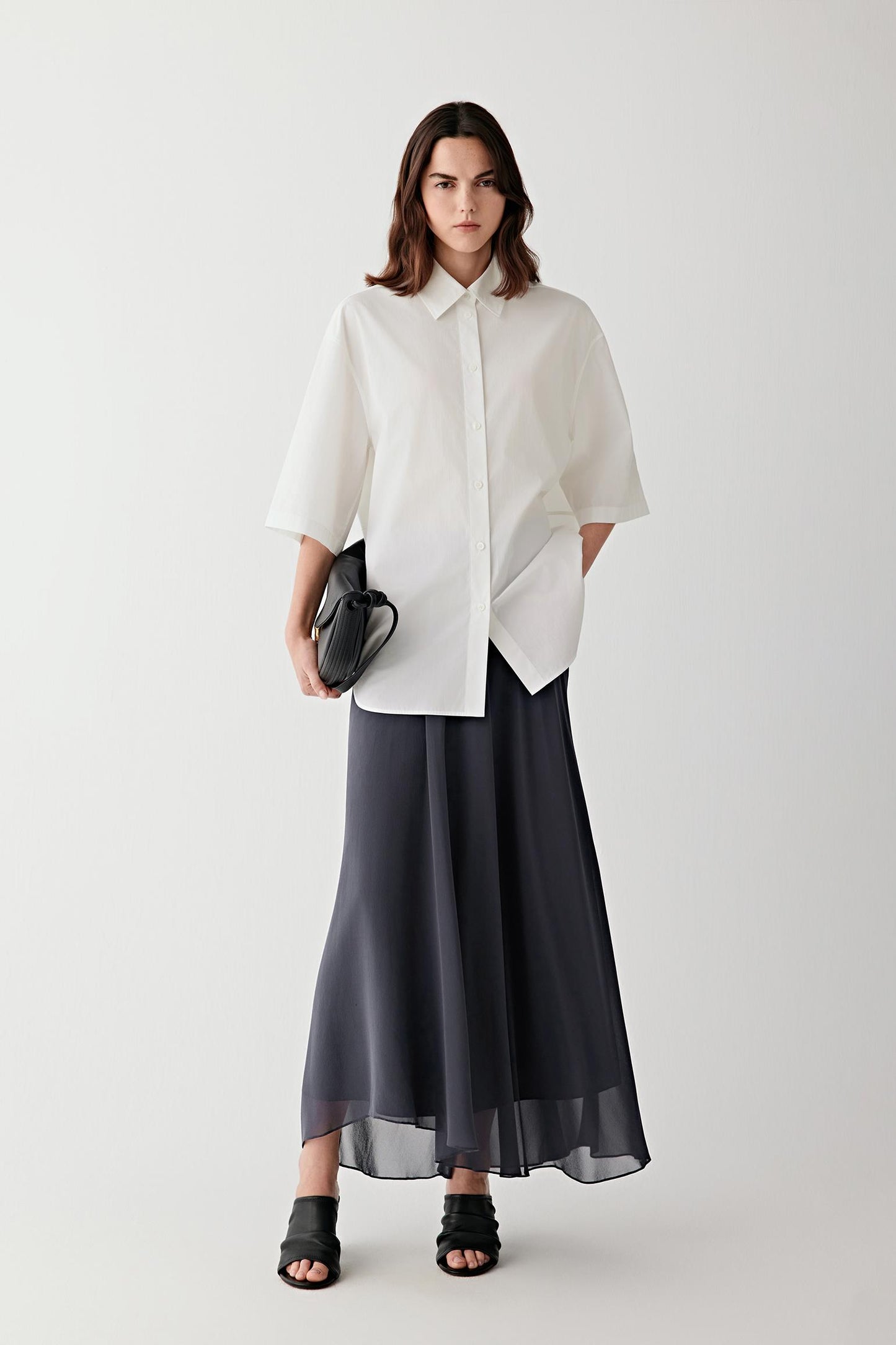 Full-length front view of a woman wearing a deep blue silk georgette skirt, highlighting the fluid drape, lightweight structure and softly matte surface