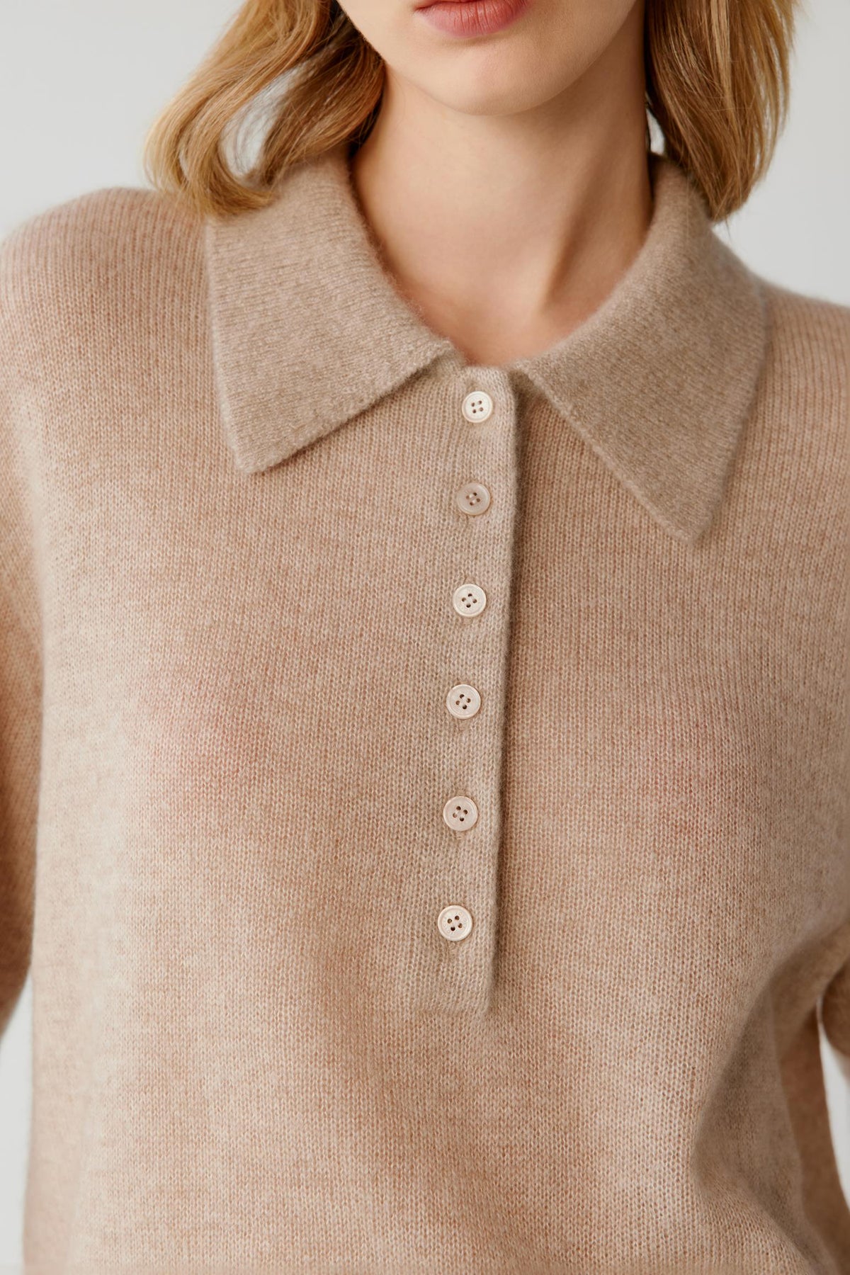 Close-up highlighting the pointed collar, partial button placket and fine-knit texture of the beige cashmere and silk top.