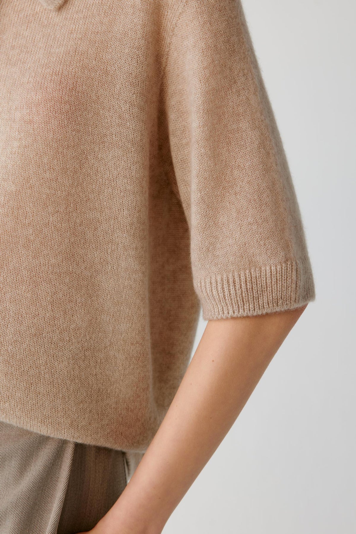 Close-up highlighting the elbow-length sleeve and fine-knit texture of the beige cashmere and silk top.