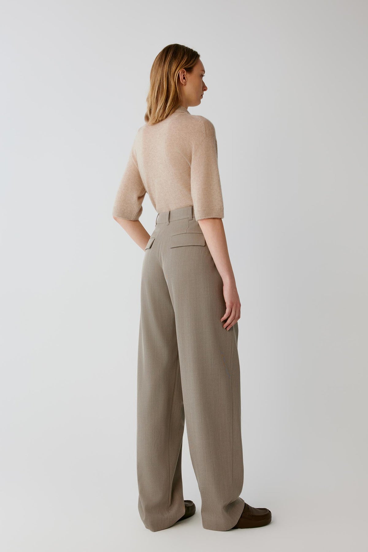 Back full-length view of a woman wearing the beige cashmere and silk top, showing the straight silhouette and clean knit construction.